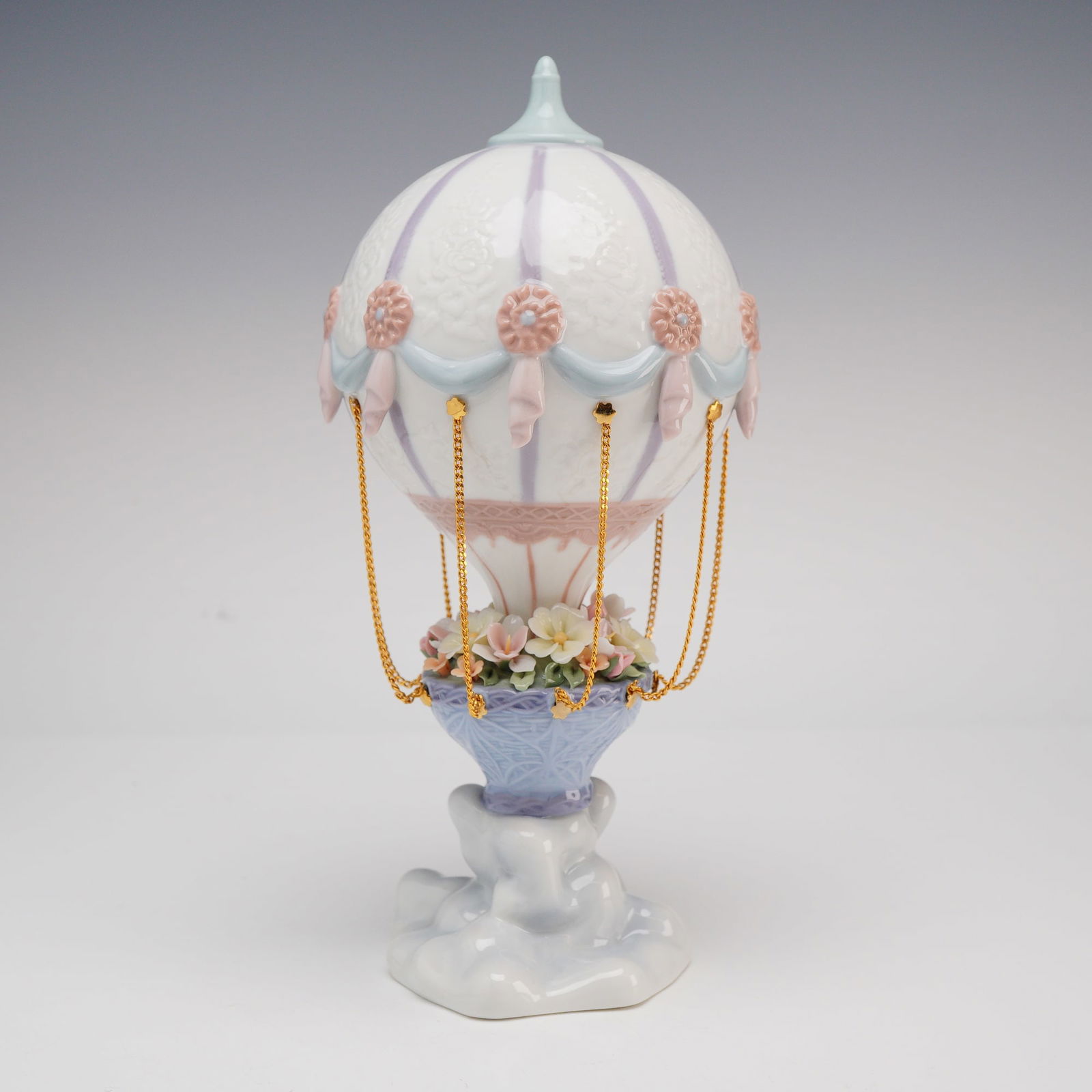 Lladro Fantasy Balloon Porcelain Figurine Model 5824: A Lladro glazed porcelain figurine titled Fantasy Balloon, model number 5824, designed by artist Joan Coderch. The piece features a whimsical hot air balloon with a white envelope accented by