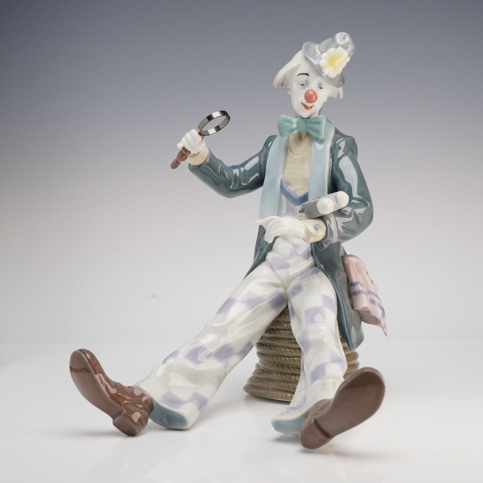 Lladro Porcelain Figurine Checking The Time (Model 5762): A Lladro glazed porcelain figurine titled Checking The Time, model number 5762, from the Circus Days collection. This finely detailed piece depicts a seated clown perched upon a coiled rope, dressed