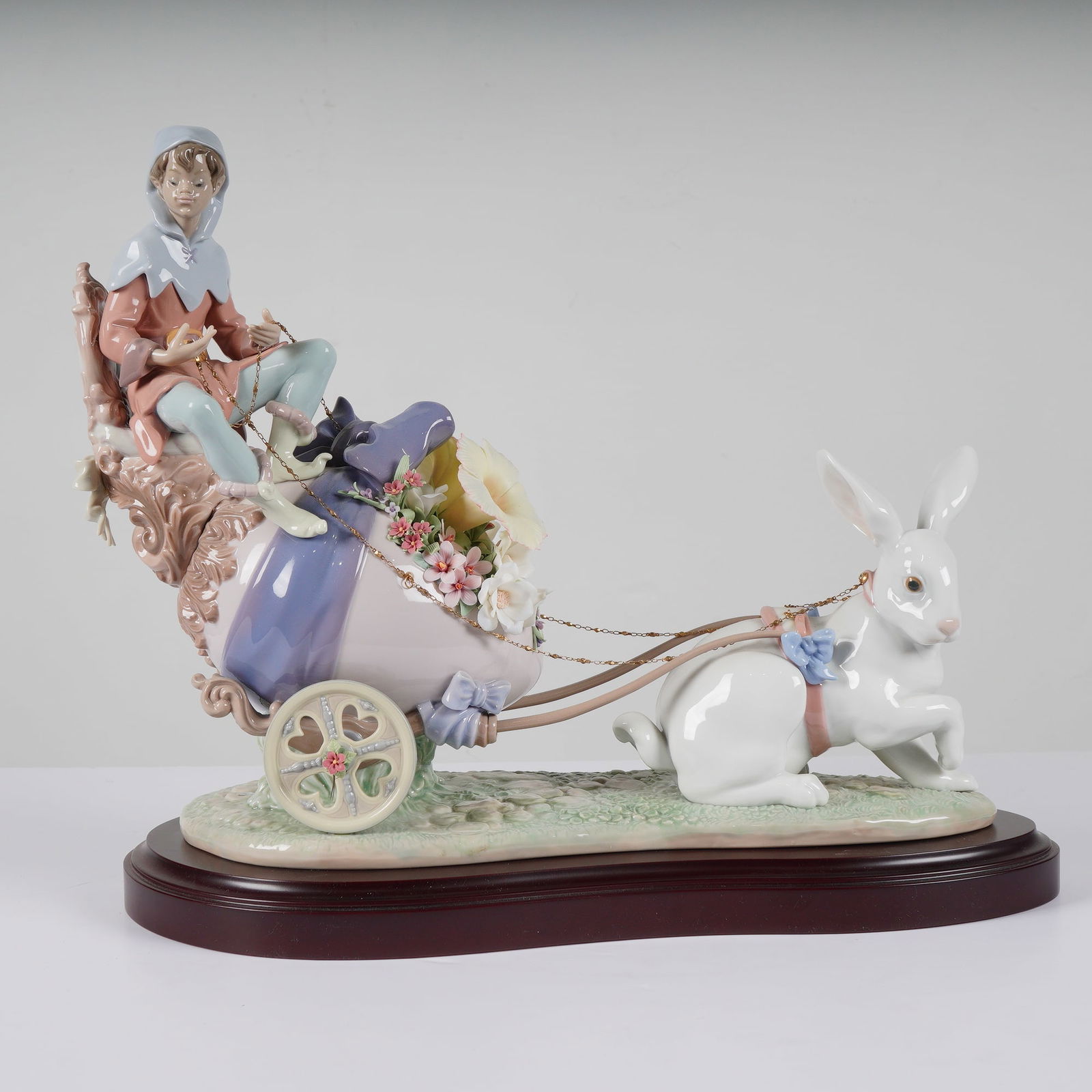 Lladro Porcelain Sculpture Easter Fantasy 1001810: This fine Lladro glazed porcelain figural group, titled "Easter Fantasy" (model 1001810), was released in 1995 as a limited edition. The piece features a whimsical scene of a young figure in a lilac a