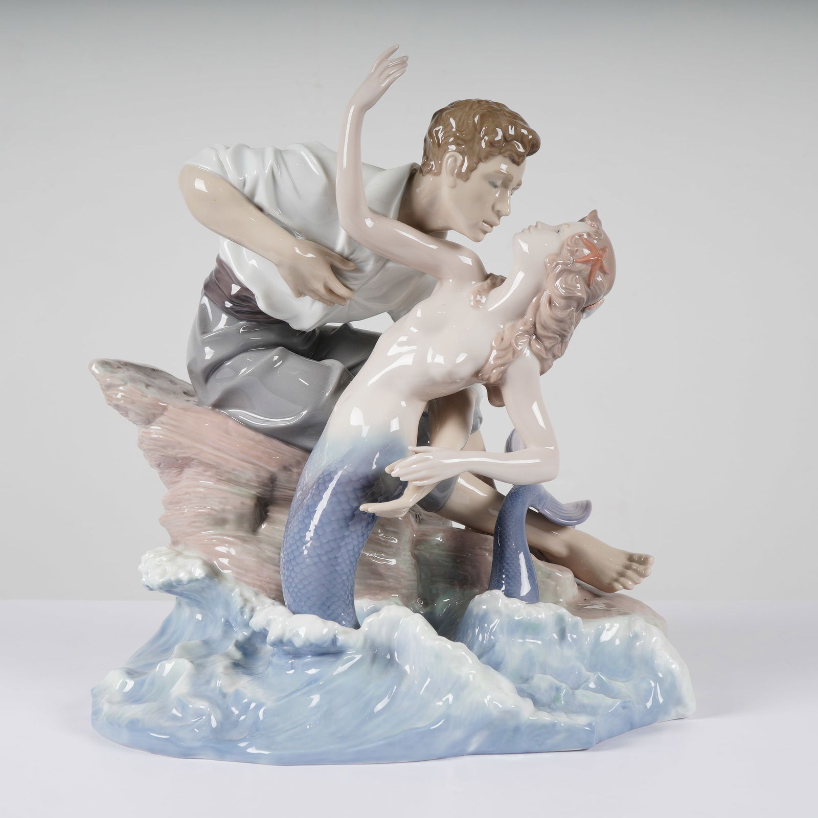 Lladro Sea of Love Porcelain Figurine Model 1006432: A large and romantic Lladro fine glazed porcelain group titled Sea of Love, model number 1006432. Designed by sculptor Joan Coderch, the scene depicts a young man in a billowing white shirt and gray t