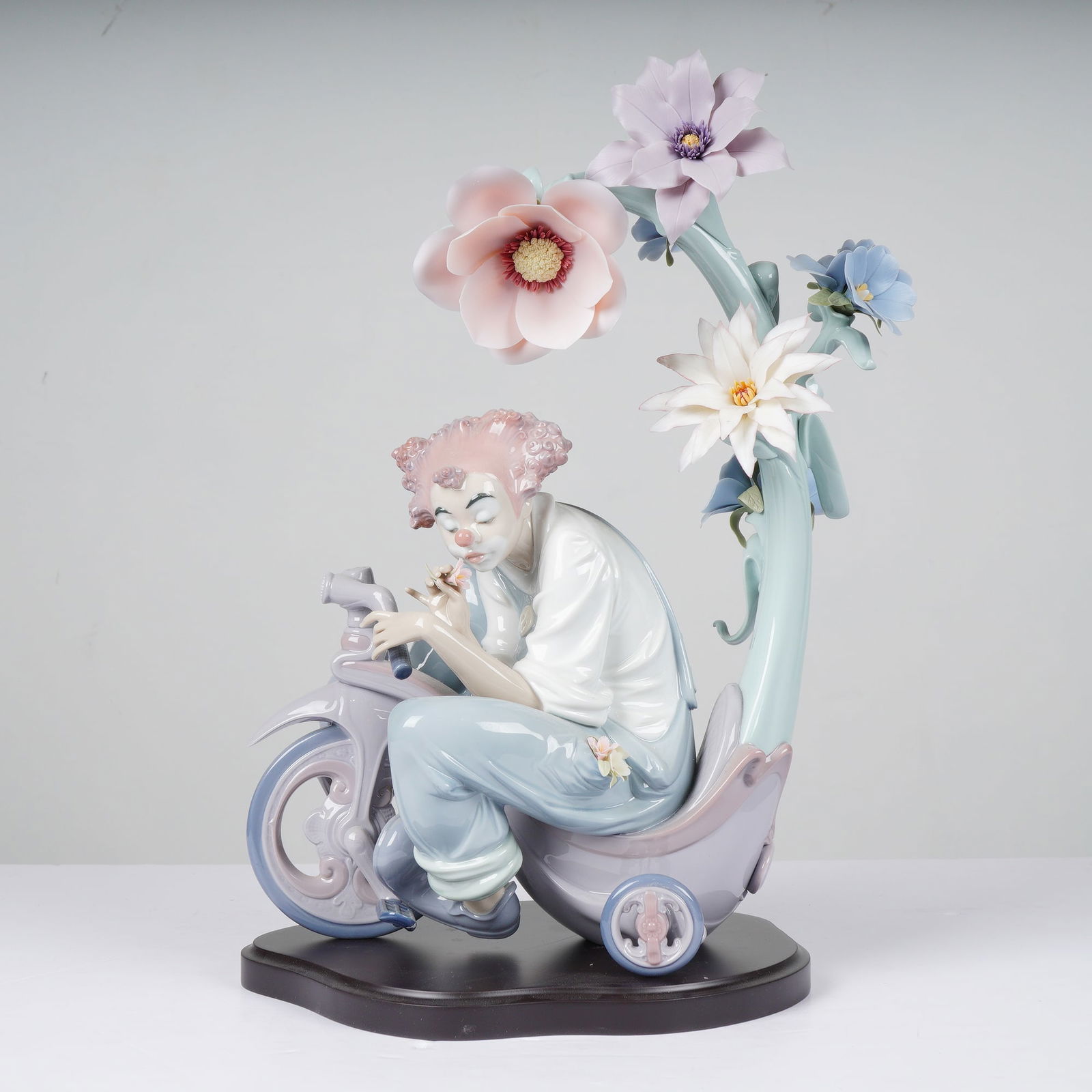 Lladro A World of Magic (Model 1001887): Lladro, model 1001887, A World of Magic. This intricate sculpture depicts a clown in a moment of reflection, seated upon a stylized tricycle beneath a towering, gracefully curved branch adorned with