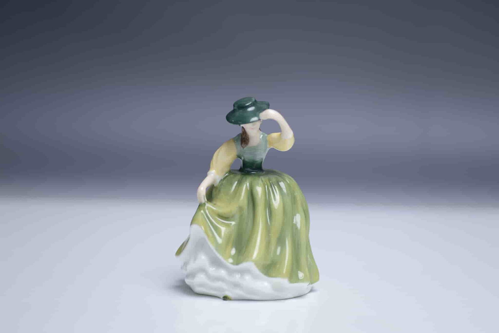 Royal Doulton Buttercup Miniature Figurine HN 3268: This is the Royal Doulton Buttercup miniature figurine, HN 3268, designed by Peggy Davies. This dainty collectible portrays a young lady in a flowing green dress with soft yellow accents, elegantly ti