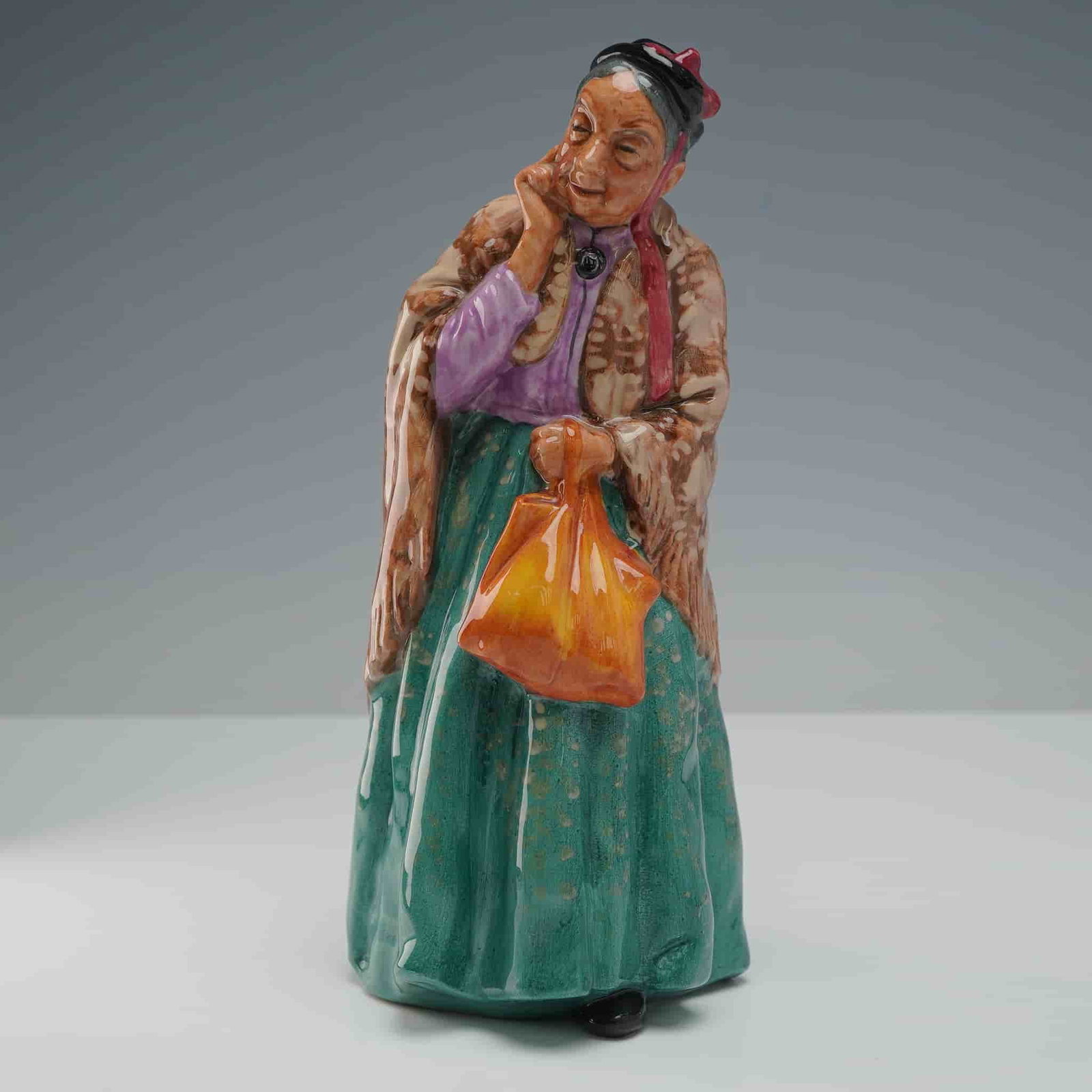 Royal Doulton Figurine, Bridget HN2070: Part of the Harradine Classics series. Depicts a sweet old lady with her shawl and handbag going out for a stroll through the park. Green, brown and lavender coloration. Royal Doulton backstamp. Artis