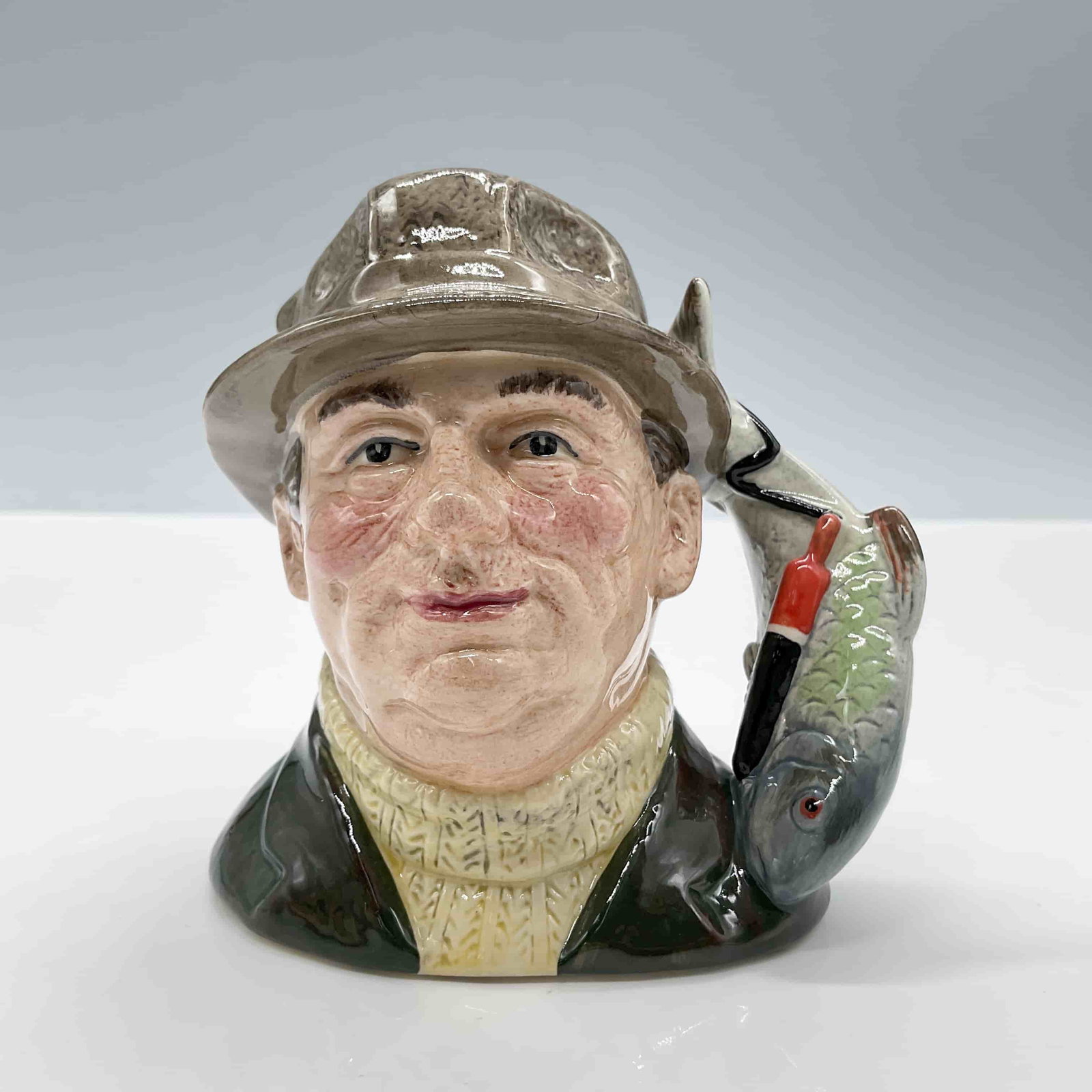 Angler Lure Handle D6866 Small Royal Doulton Character Jug: Style One, fish and lure handle. Green jacket; brown hat; cream pullover. Royal Doulton backstamp. ArtistStanley J. Taylor Dimensions4.75''L x 3.25''W x 4"H Date or Era1990 - 1995 Manufacturer or Bran