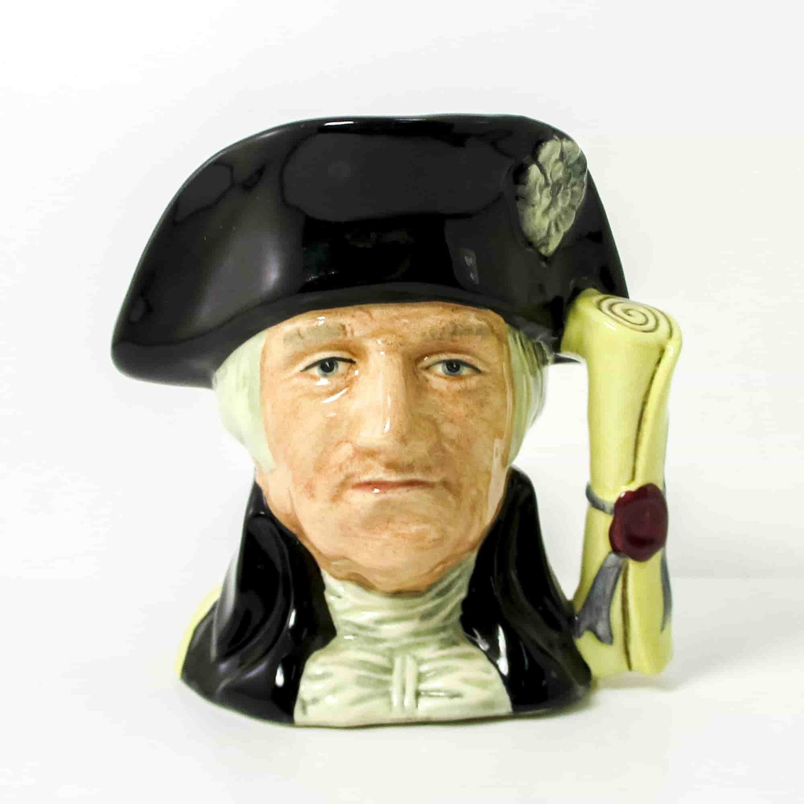 George Washington D6824 Small Royal Doulton Character Jug: Style One, Declaration of Independence handle. Black hat and coat; beige shirt. Royal Doulton backstamp. ArtistStanley J. Taylor Dimensions4"H Date or Era1989 - 1991 Manufacturer or BrandRoyal Doulton