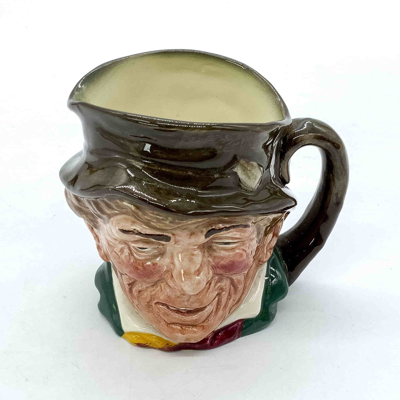 Paddy D5768 - Small - Royal Doulton Character Jug: Brown hat; green coat; yellow and red scarf. Paddy, a colloquial term for an Irishman, is derived from St. Patrick, the country's patron saint. This gent is dressed in traditional green for St. Patric