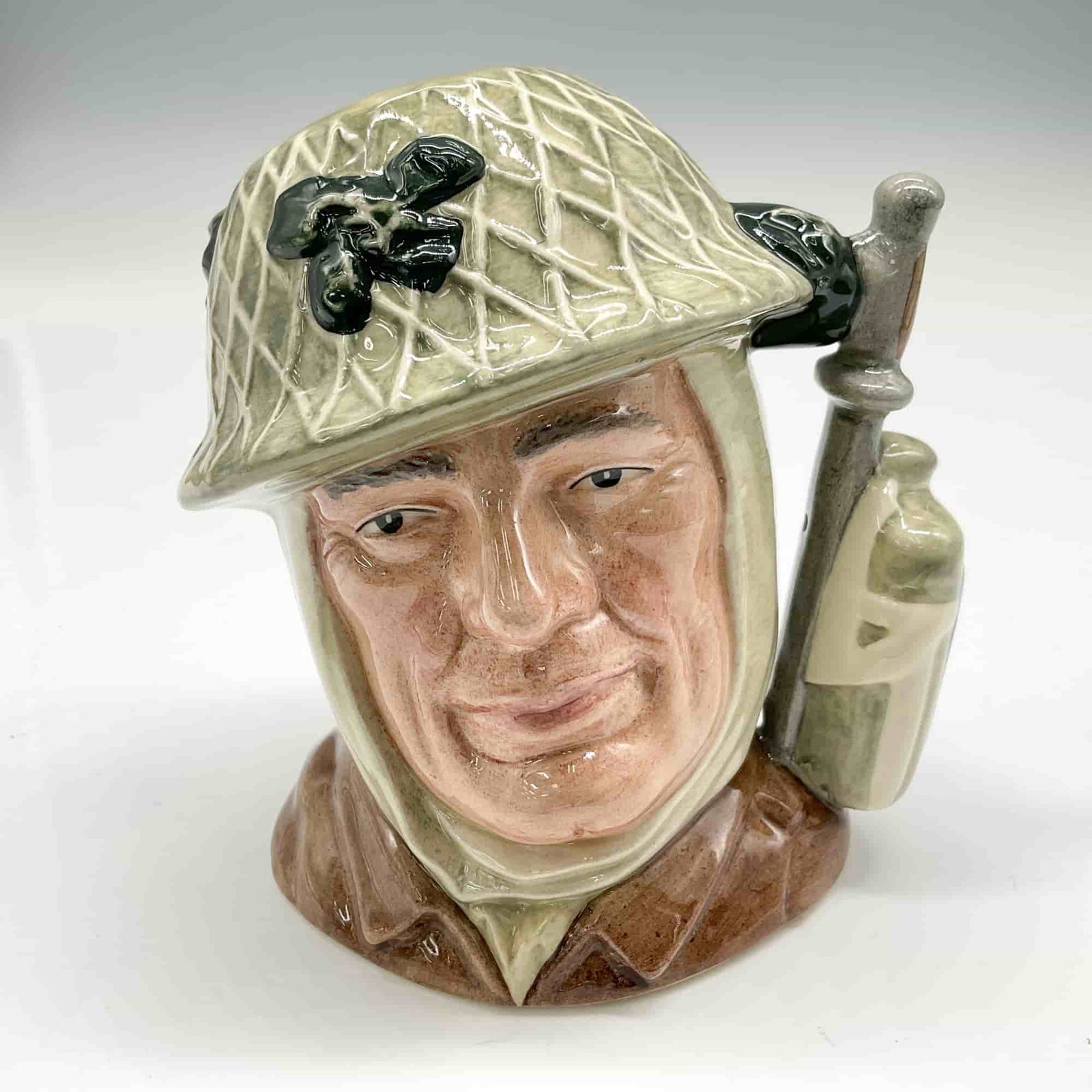 Soldier D6876 - Small - Royal Doulton Character Jug: Style One, Variation One, desert rat patch on canteen. Army steel helmet with netting; khaki tunic. Royal Doulton backstamp. ArtistWilliam K. Harper Dimensions4.5"H Date or Era1991 - 1996 Manufacturer