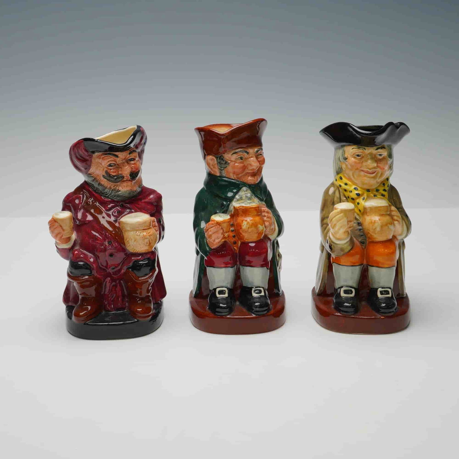 3pc Royal Doulton Small Toby Jugs- Falstaff, Old Charlie & Happy John: A set of three Royal Doulton small character toby jugs, including Falstaff, Old Charlie, and Happy John. Each finely hand painted in vibrant colors with expressive facial detail, depicting 18th centur