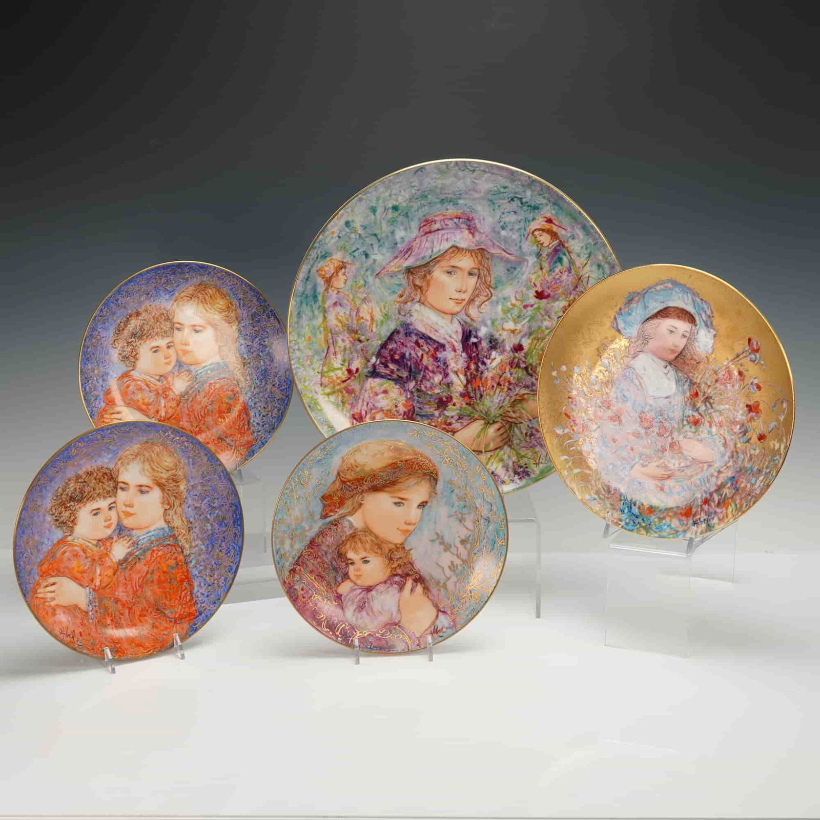 5pc Hutschenreuther, Hibel, & Edwin M. Knowles Edna Hibel Collector Plates: Five limited edition plates and decorated with her signature impressionistic portraits of mothers and children. Decorated with 22 kt gold embellishments. One plate is entitled "Lily" and is no. 3202