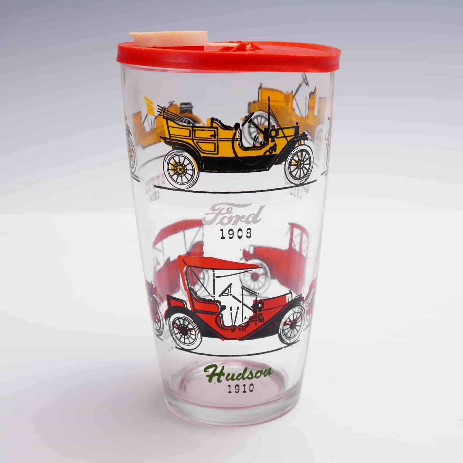 2pc Anchor Hocking Classic Cars Glass with Lid: 2pc set including a vintage Anchor Hocking drinking glass decorated with colorful illustrations of early American automobiles such as Ford 1908 and Hudson 1910, along with its original red plastic lid