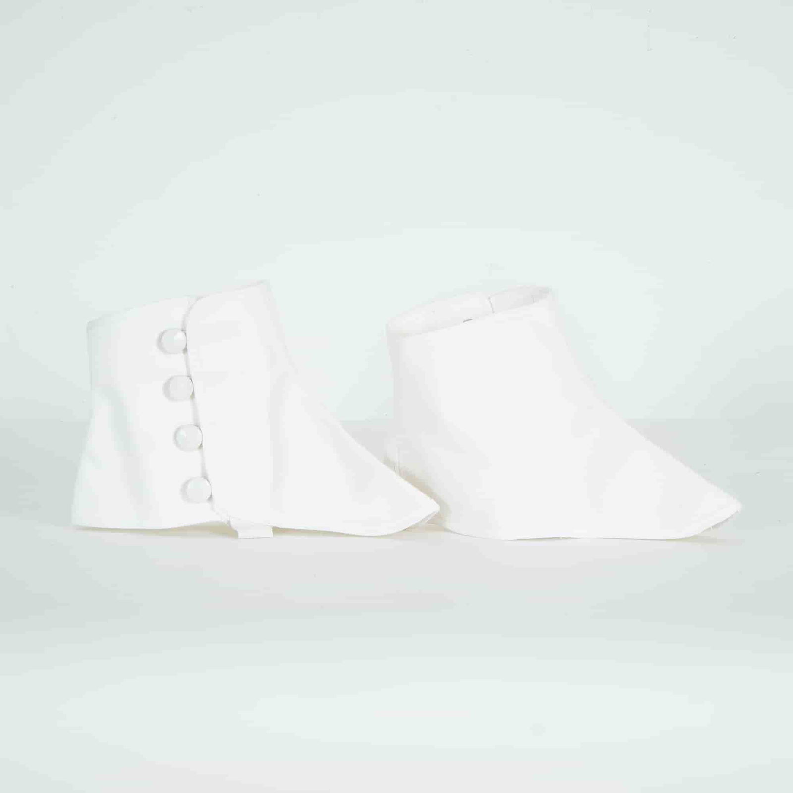 Pair of White Cotton Spats: This pair of white cotton spats presents a traditional silhouette distinguished by its structured form, buttoned closure, and underfoot strap, designed to envelop the ankle. Dimensions9.5"W x 6.5"H