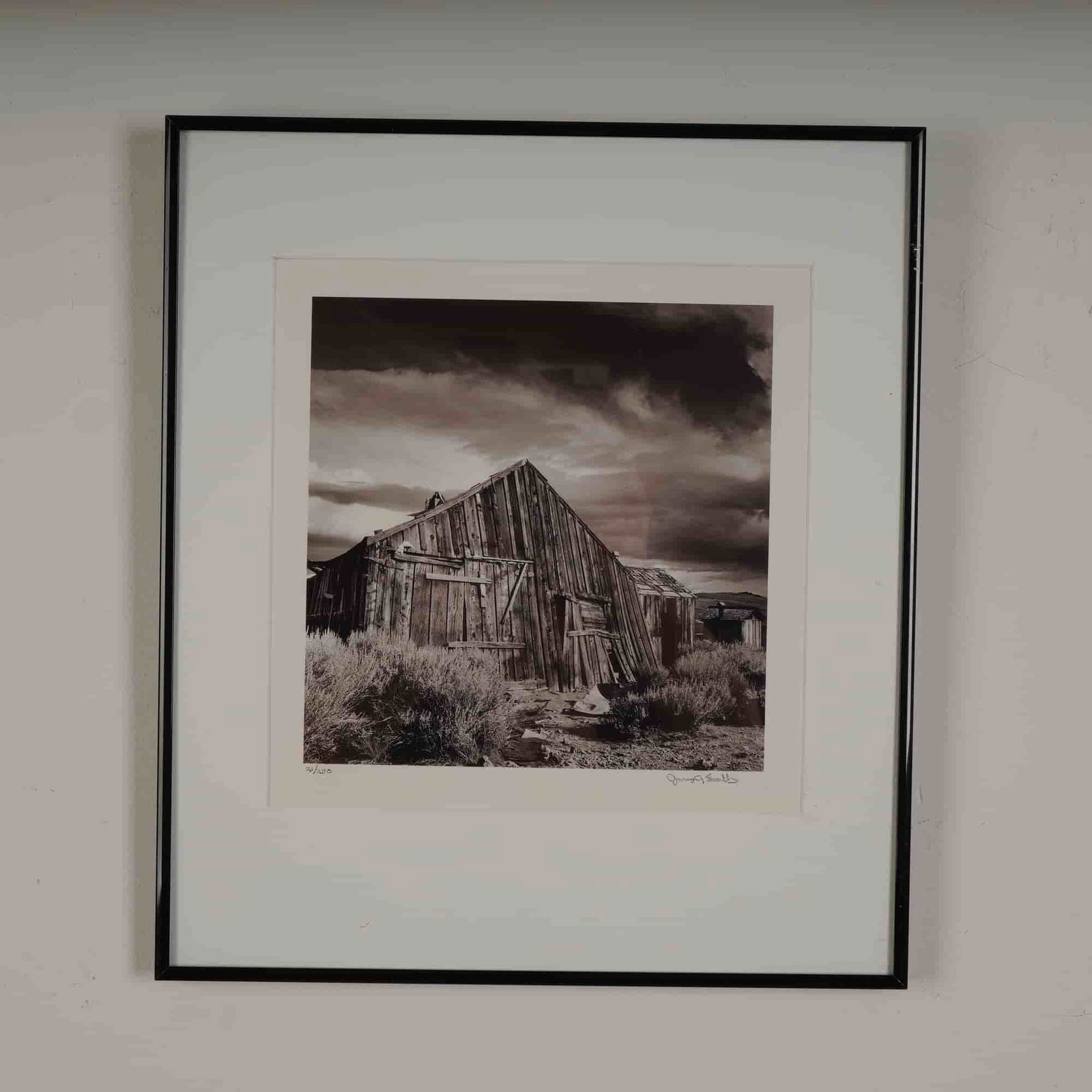 James A Swallow, B&W Photograph, Waiting till the Next, Signed: A striking limited edition black and white photograph by James A. Swallow, titled Waiting Till the Next. This atmospheric image captures a weathered wooden structure beneath dramatic skies in a desola