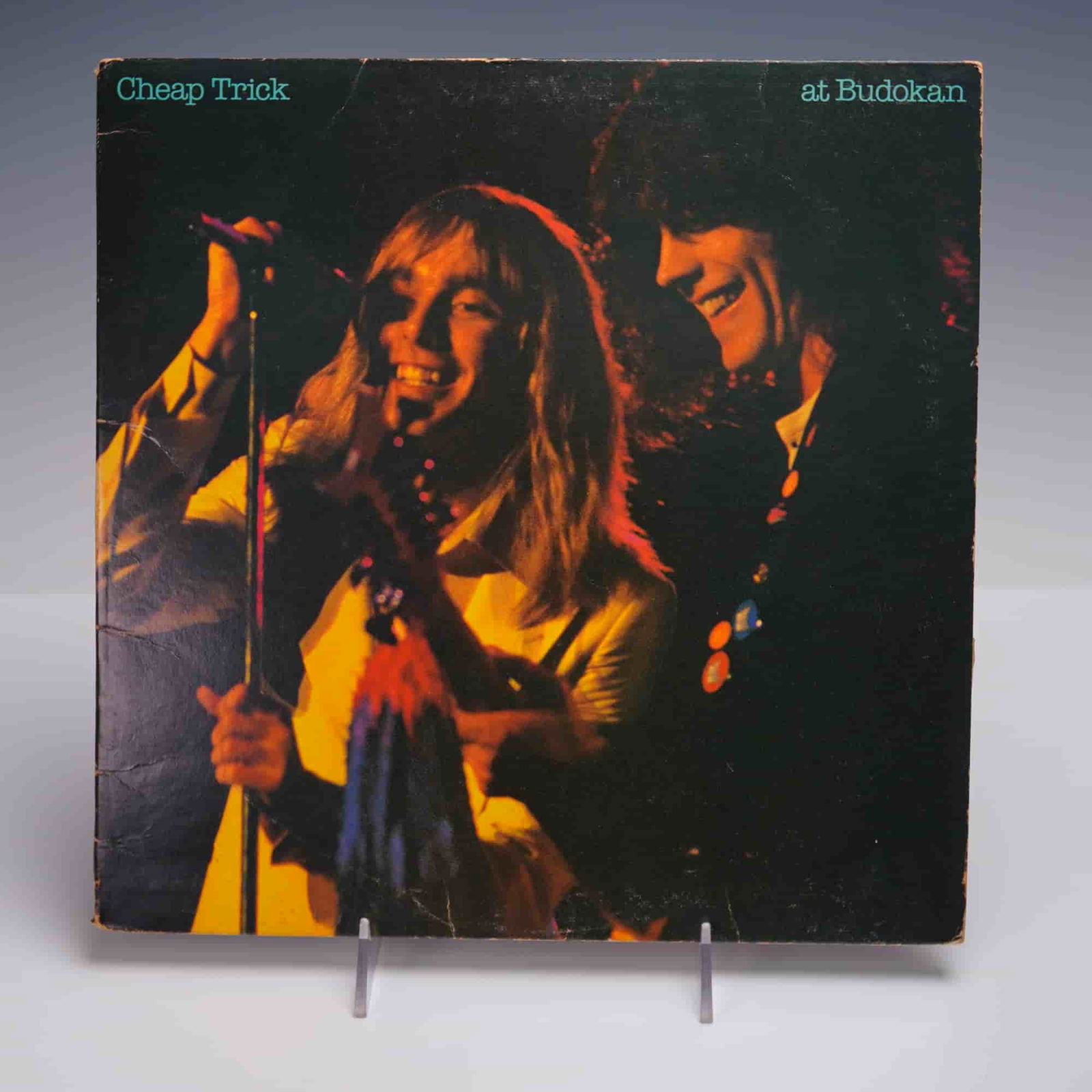Epic Records Cheap Trick Vinyl Record, Cheap Trick At Budokan: Exceptional 12-inch vinyl record featuring Cheap Trick's 1979 album released by Epic records. The front of the jacket depicts two band members while the back features the bass and drum players. Includ