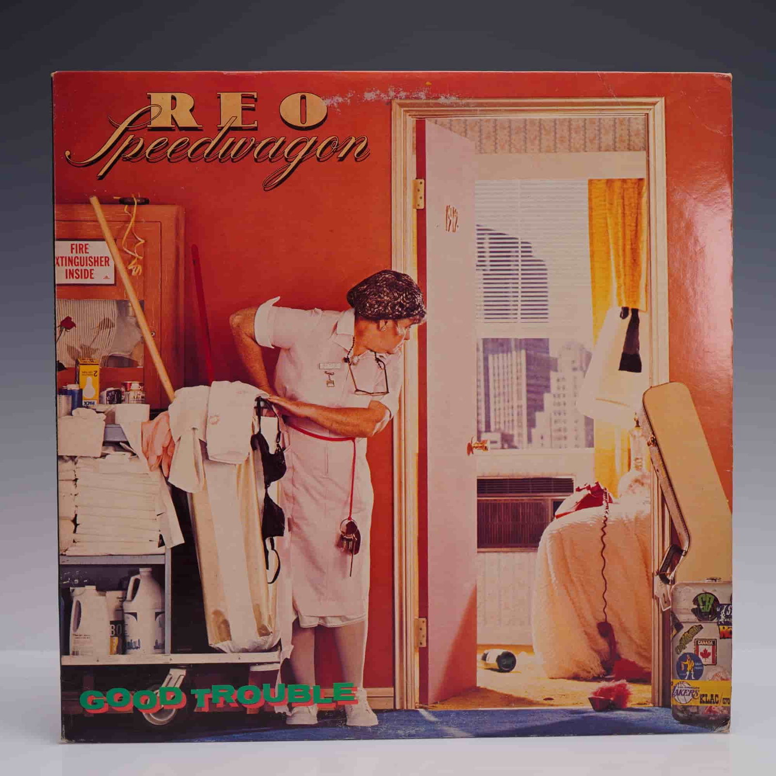 REO Speedwagon 'Good Trouble' Vinyl LP: 1982 Epic Records release of Good Trouble by REO Speedwagon that includes tracks like 'Keep the Fire Burnin'', 'Sweet Time', and 'I'll Follow You'. Features cover art with a hotel maid caught mid-scen