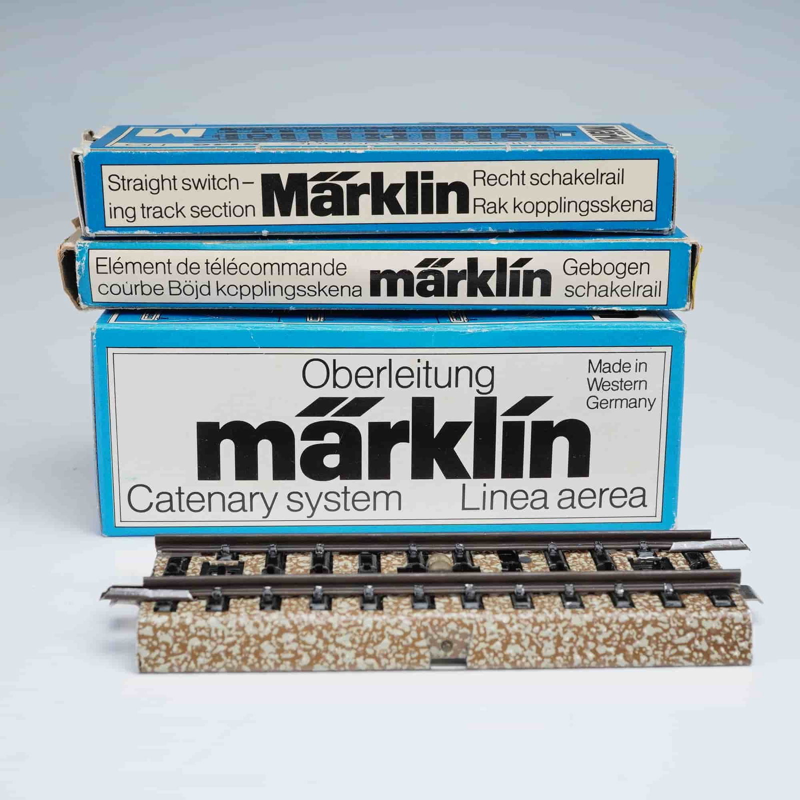 3pc Marklin HO Scale Railroad Model Parts Set: Lot of three Marklin HO scale model railroad components including one catenary system section No. 7009, one curved switching track section No. 5147, and one straight switching track section No. 5146.