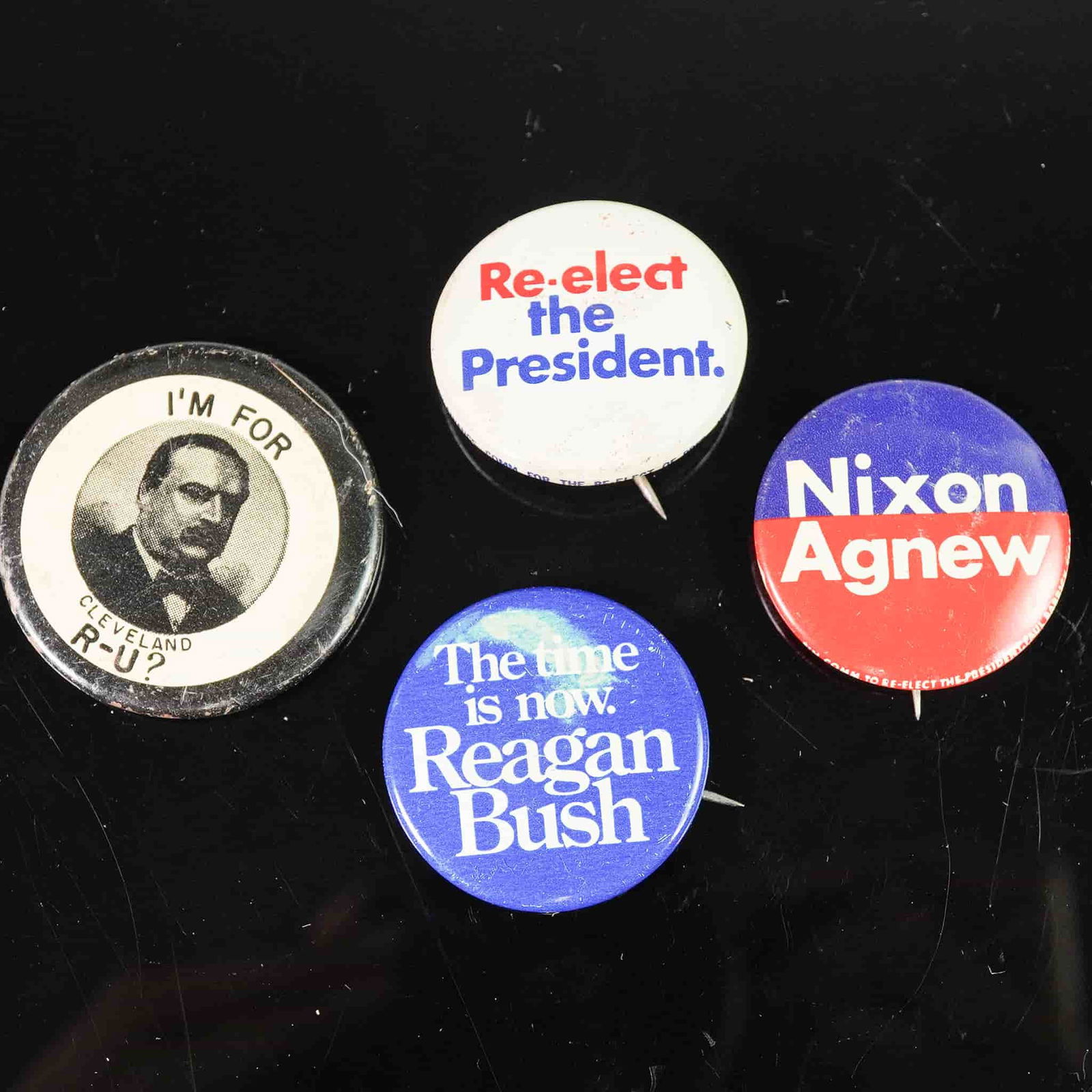 4pc Political Campaign Button Lot: Group of four pin-back political buttons including slogans for Nixon-Agnew, Reagan-Bush, and Re-elect the President, along with a novelty button reading I'm for Cleveland R-U? referencing Grover