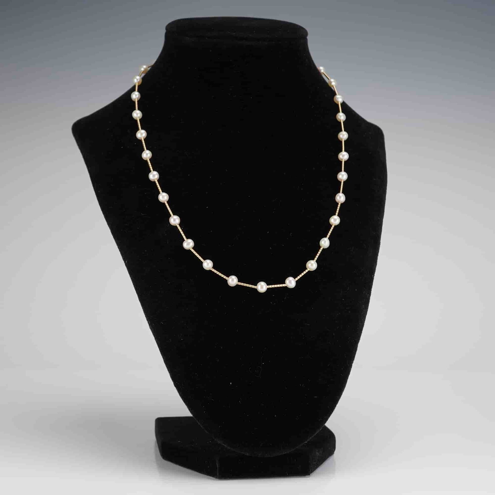 14K Yellow Gold Twist Tube and Pearl Station Necklace: A contemporary station necklace constructed of 14K yellow gold and featuring 24 individually spaced cultured pearls. The necklace is composed of a fine, twisted rope-link chain, often referred to in