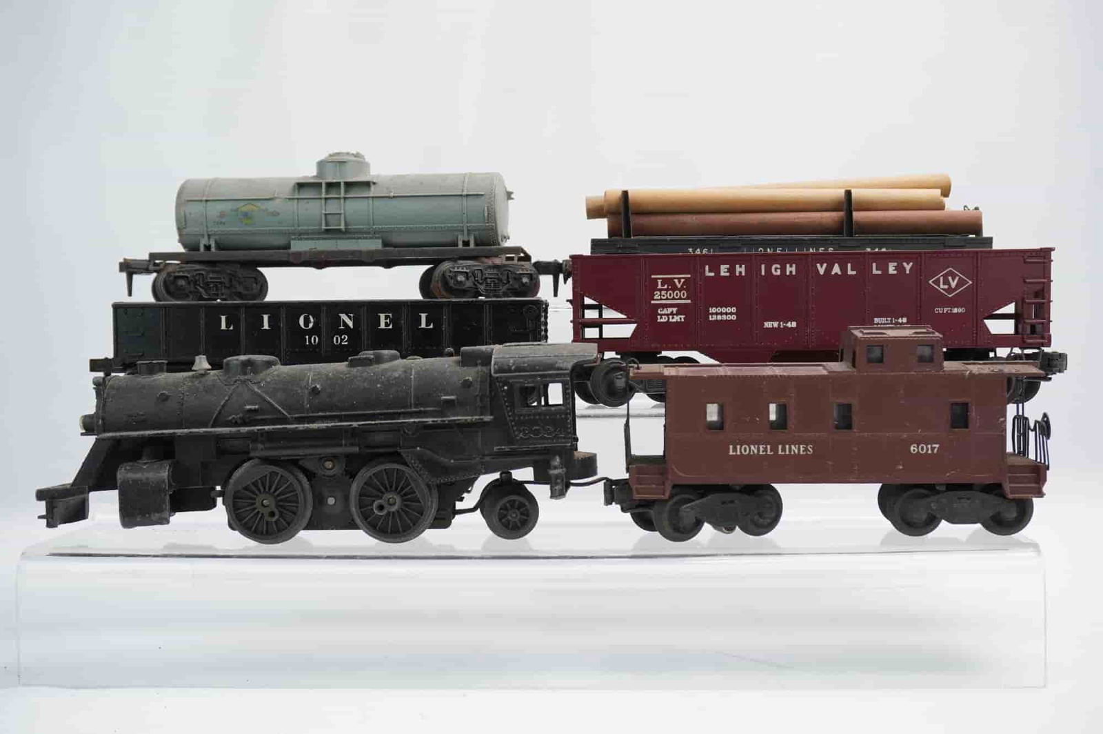 6pc Lionel Postwar O/O-27 Gauge Model Train Components: A collection of five Lionel Postwar O/O-27 gauge model train components, constructed from die-cast metal and composite plastic. The lot includes a black steam locomotive, a pale green tank car, a blac