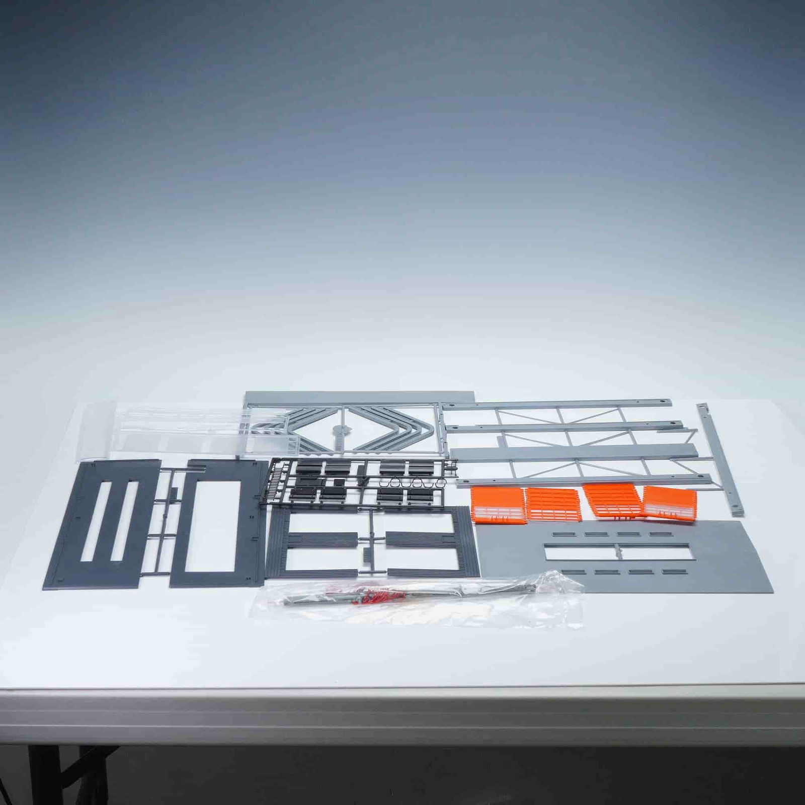 Marklin HO Bausatz Lokomotivschuppen Model Kit: Marklin HO Bausatz Lokomotivschuppen plastic model kit, complete and unassembled, featuring gray structural frame pieces, orange window panels, black detail sprues, clear plastic sections, and sealed