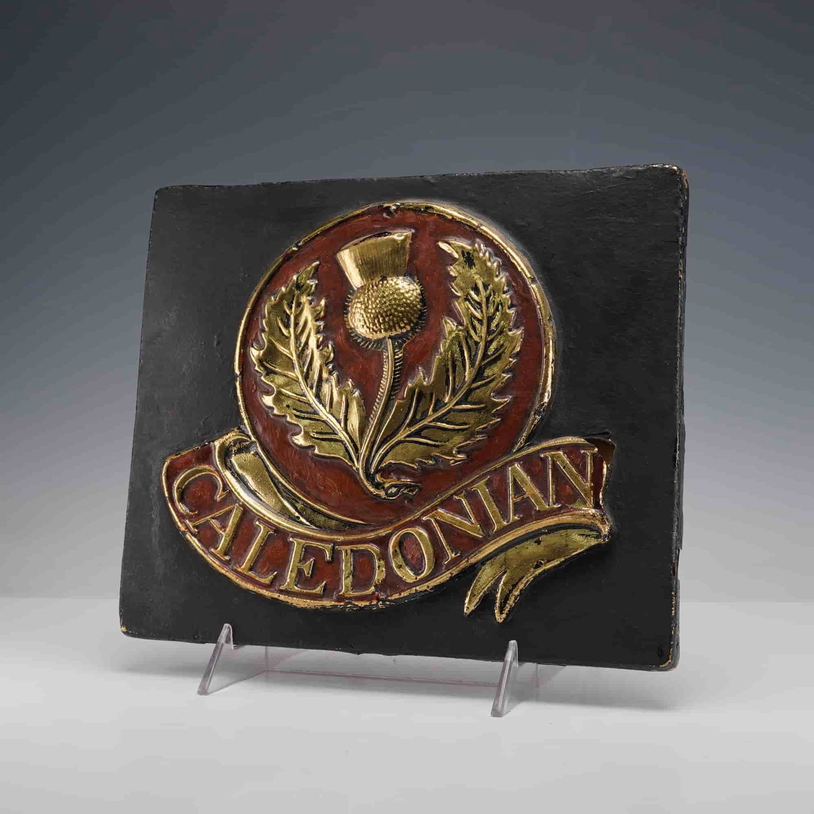 Caledonian Insurance by E. V. Jackson Reproduction Fire Mark Plaque: This plaque has a raised gold thistle emblem with red accents and a Caledonian banner on a black backing. The reverse has a label noting it is a reproduction of an original fire mark by E. V.
