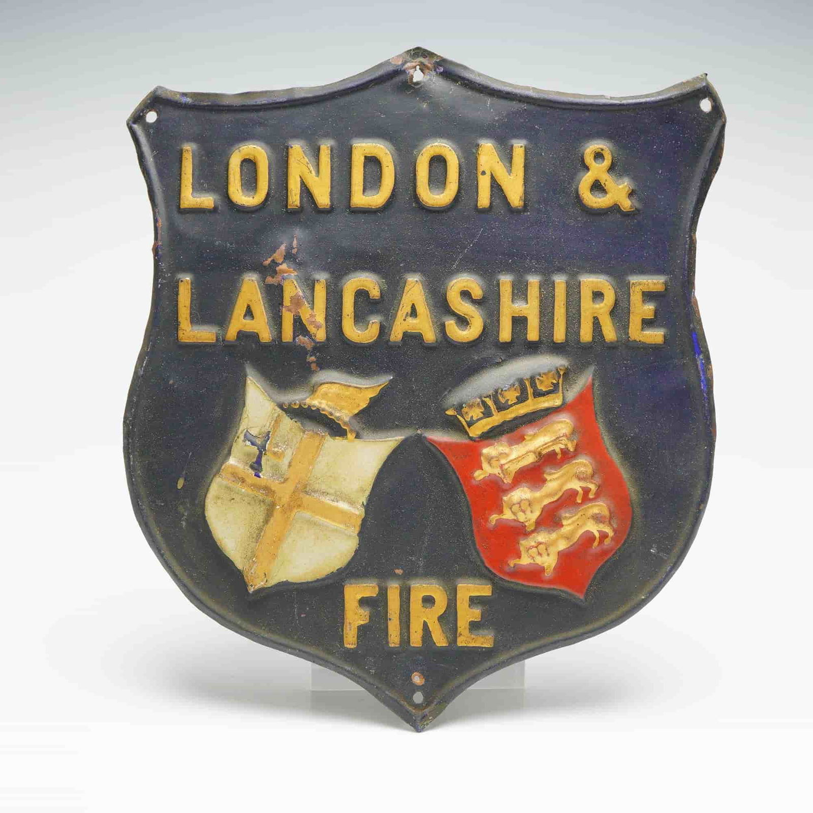 London and Lancashire Fire Insurance Pressed Metal Advertising Plaque: This pressed metal wall plaque was produced for the London and Lancashire Fire Insurance Company and features a raised shield form with the company name above two embossed coats of arms. Made of light