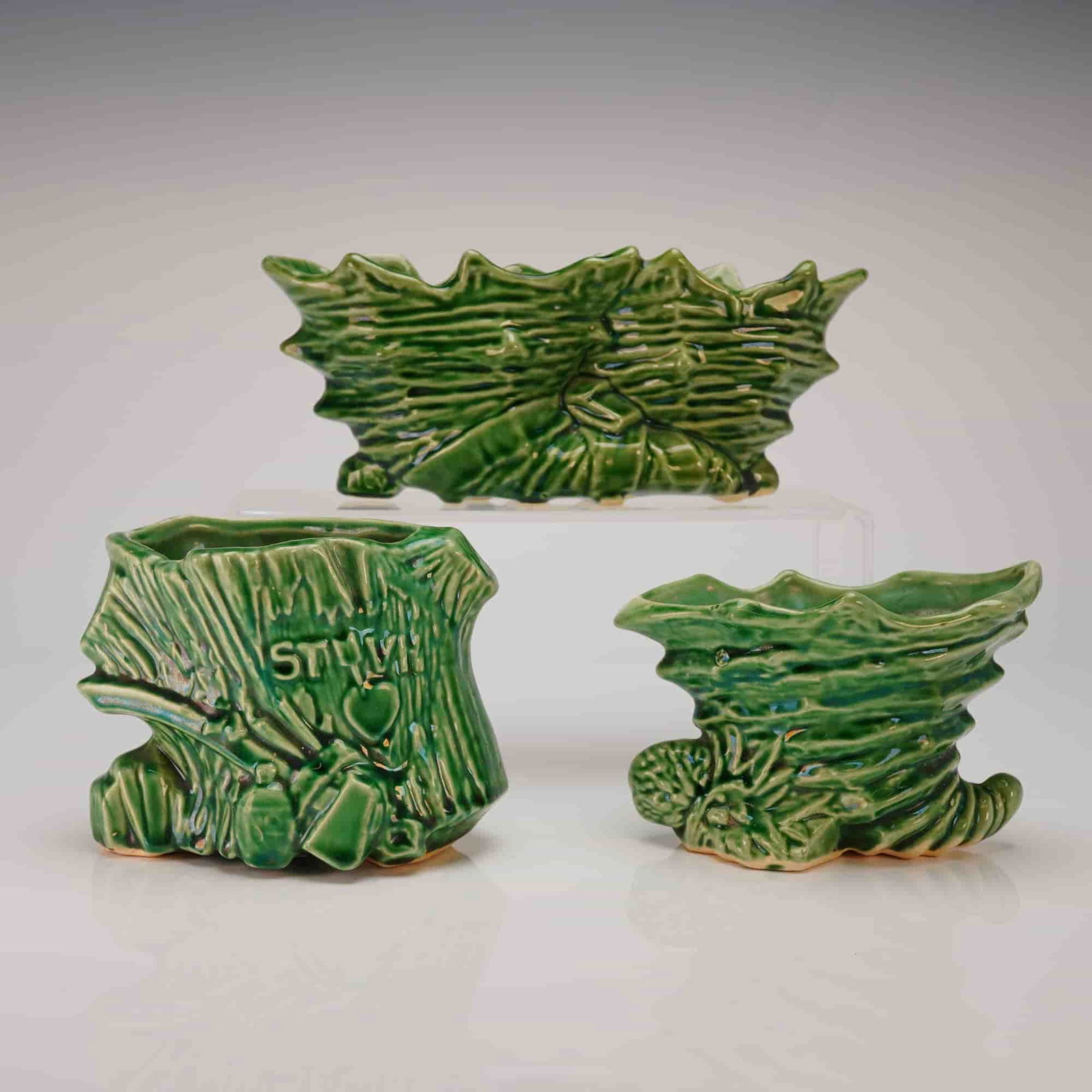Three McCoy Emerald Green Glazed Earthenware Planters: A three-piece collection of ceramic vessels attributed to McCoy, consistent with the style of their novelty planters or cachepots. The set includes one rectangular centerpiece vessel and two smaller,
