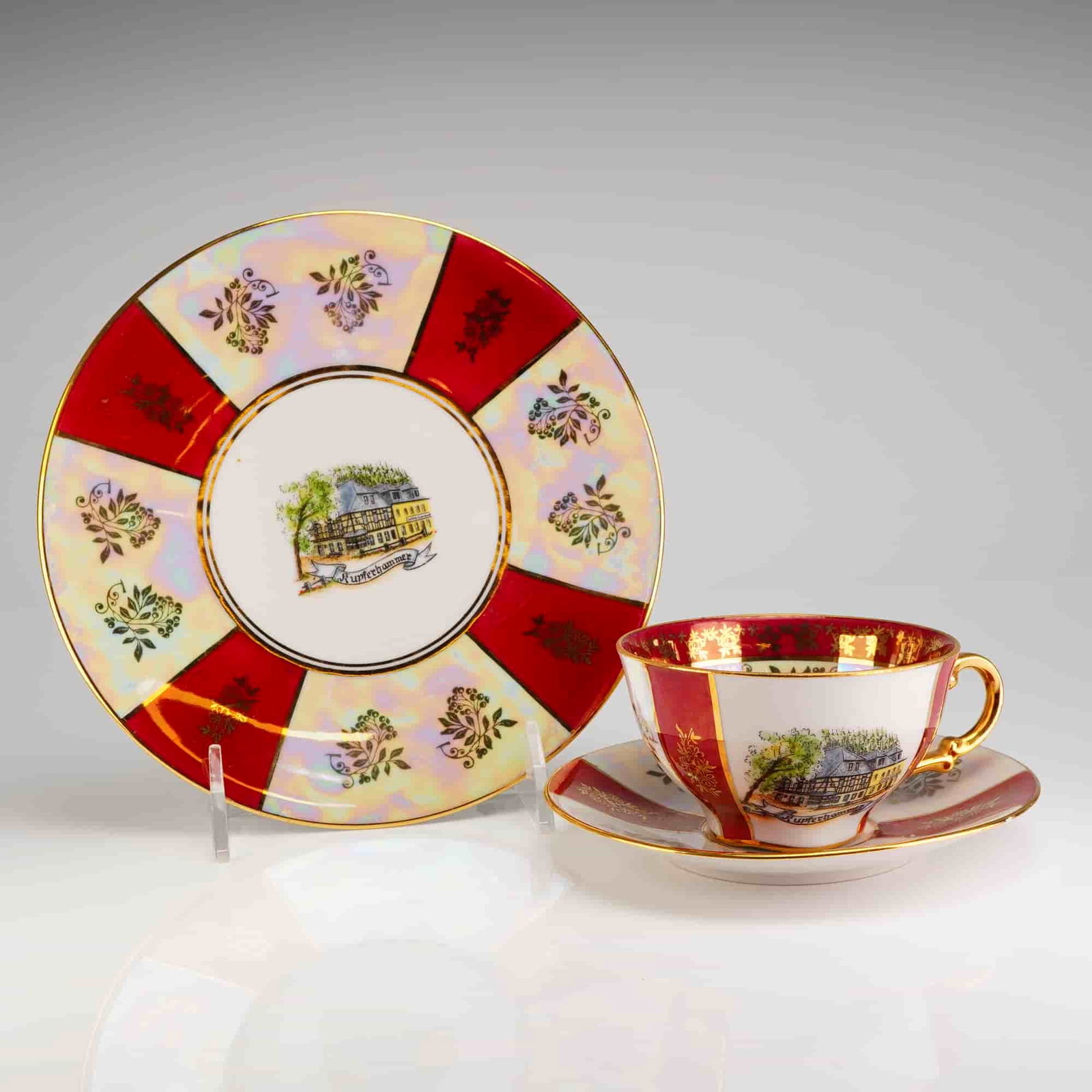 Gerold Porzellan Bavaria Trio Tea Set, Kupferhammer: This is a 3pc set, Cup, Saucer & Dessert Plate, has a white porcelain body decorated with alternating panels of deep red enamel and an iridescent luster glaze. Extensive gilt detailing is present, inc