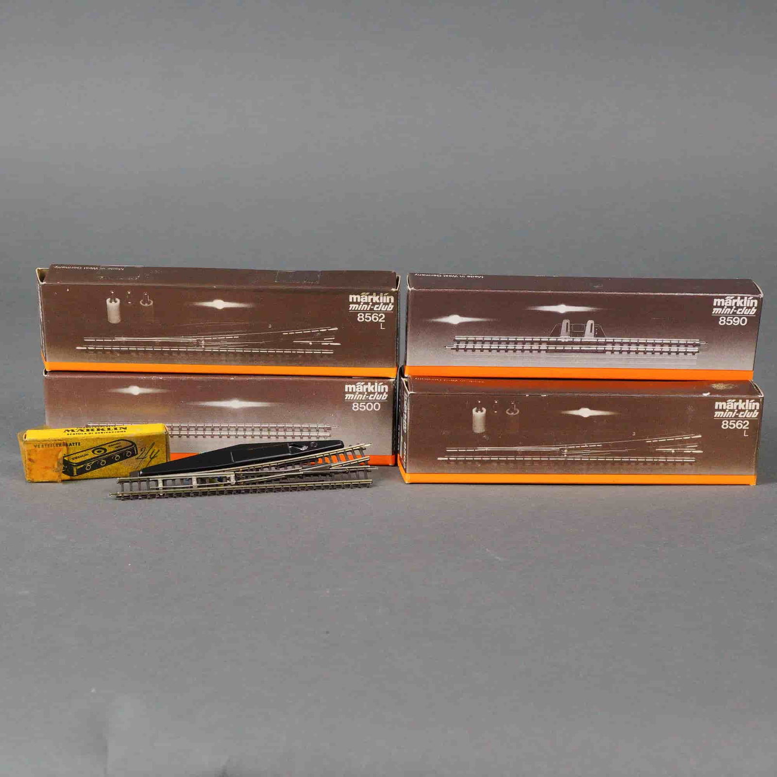 5pc Marklin Mini-Club Z-Gauge Model Railway Components: Marklin mini-club Z-gauge model railway system, primarily dating from the "Made in West Germany" period. The lot includes four long, brown cardboard boxes containing track segments or turnouts,