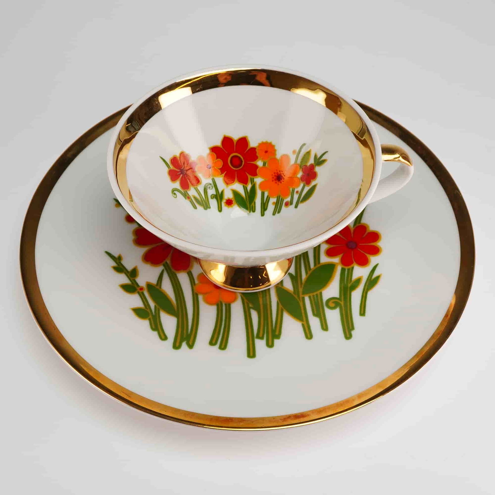 2pc Mitterteich Bavaria Porcelain Tea Set, Mid-Century Floral: The cup and saucer set is constructed of white glazed porcelain and features a distinctive Mid-Century style floral decoration. The stylized blossoms are rendered in flat applications of red, orange,