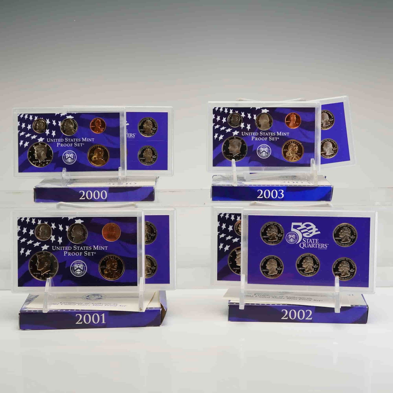 4pc 2000-2003 U.S. Mint Proof Sets: A collection of four United States Mint Proof Sets dating from 2000 to 2003. Each set features standard circulation denominations and the 50 State Quarters series for the corresponding year. The coins