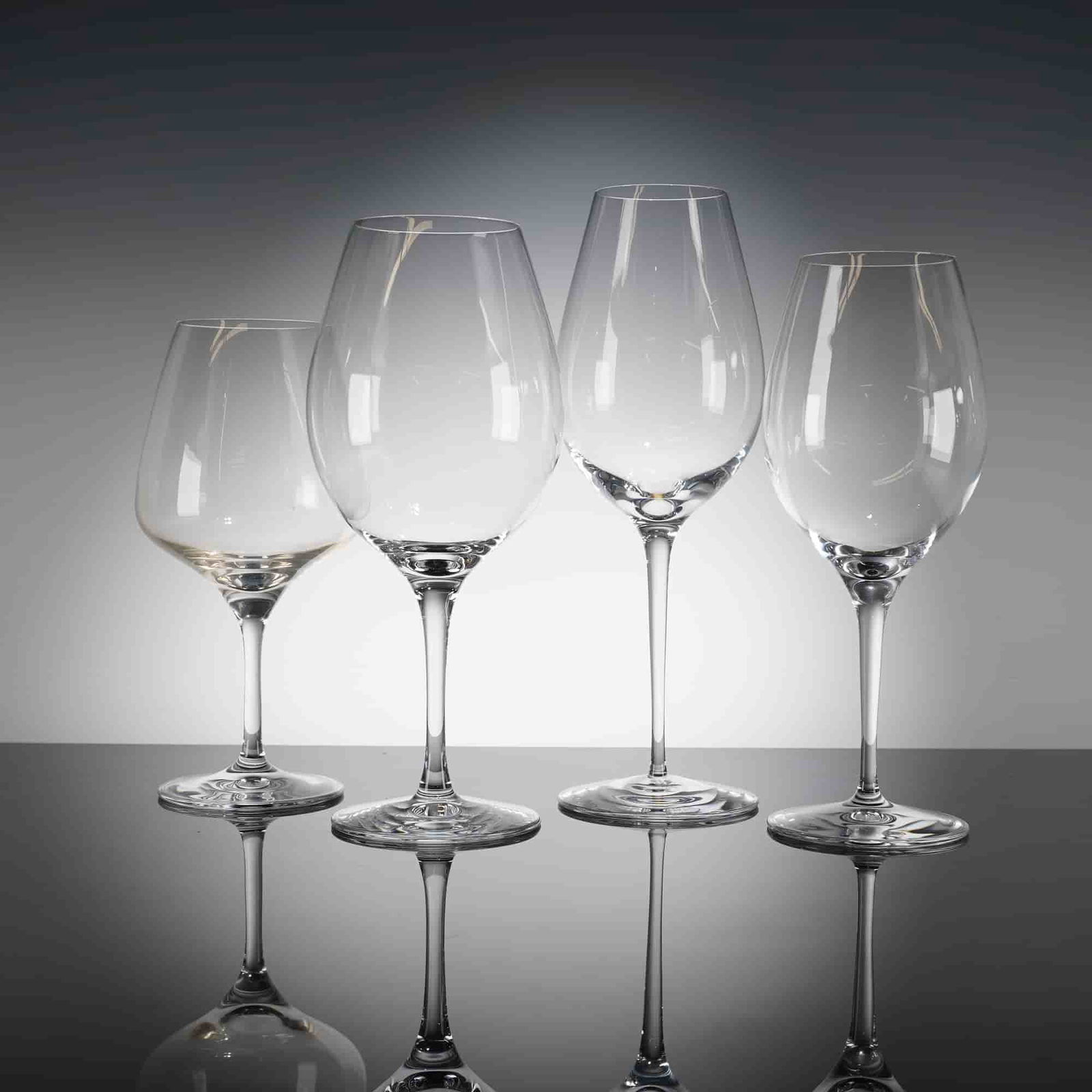 A Collection of Four Orrefors More Crystal Wine Glasses: A collection of four contemporary stemmed drinking glasses identiied as the Orrefors More Wine patern. The glasses are crafted from clear crystal, featuring inely blown bowls of varying shapes and