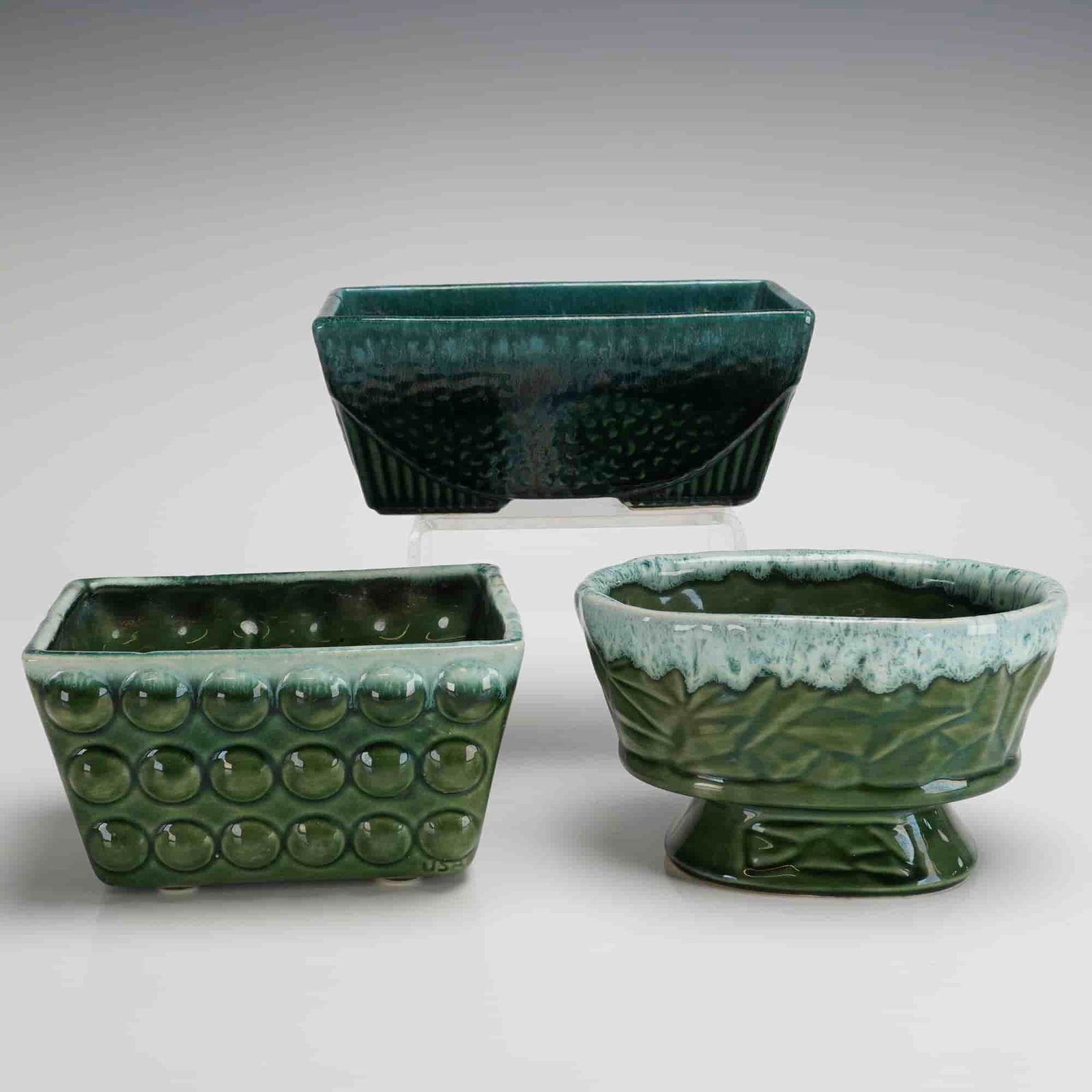 Three McCoy Pottery Green Glazed Jardinieres: A trio of glazed ceramic planters, or jardinieres, attributed to McCoy Pottery, consistent with designs produced during the 1930s Majolica revival period. The collection is finished primarily in