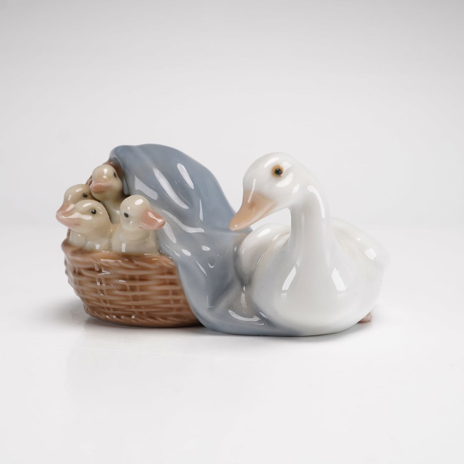 Lladro Porcelain Figurine, Duckling 1004895: This fine glazed porcelain figurine by Lladro is titled Duckling, model number 4895. Designed by Juan Huerta, the piece was first issued in 1974 and retired in 2004. It depicts a mother duck resting b