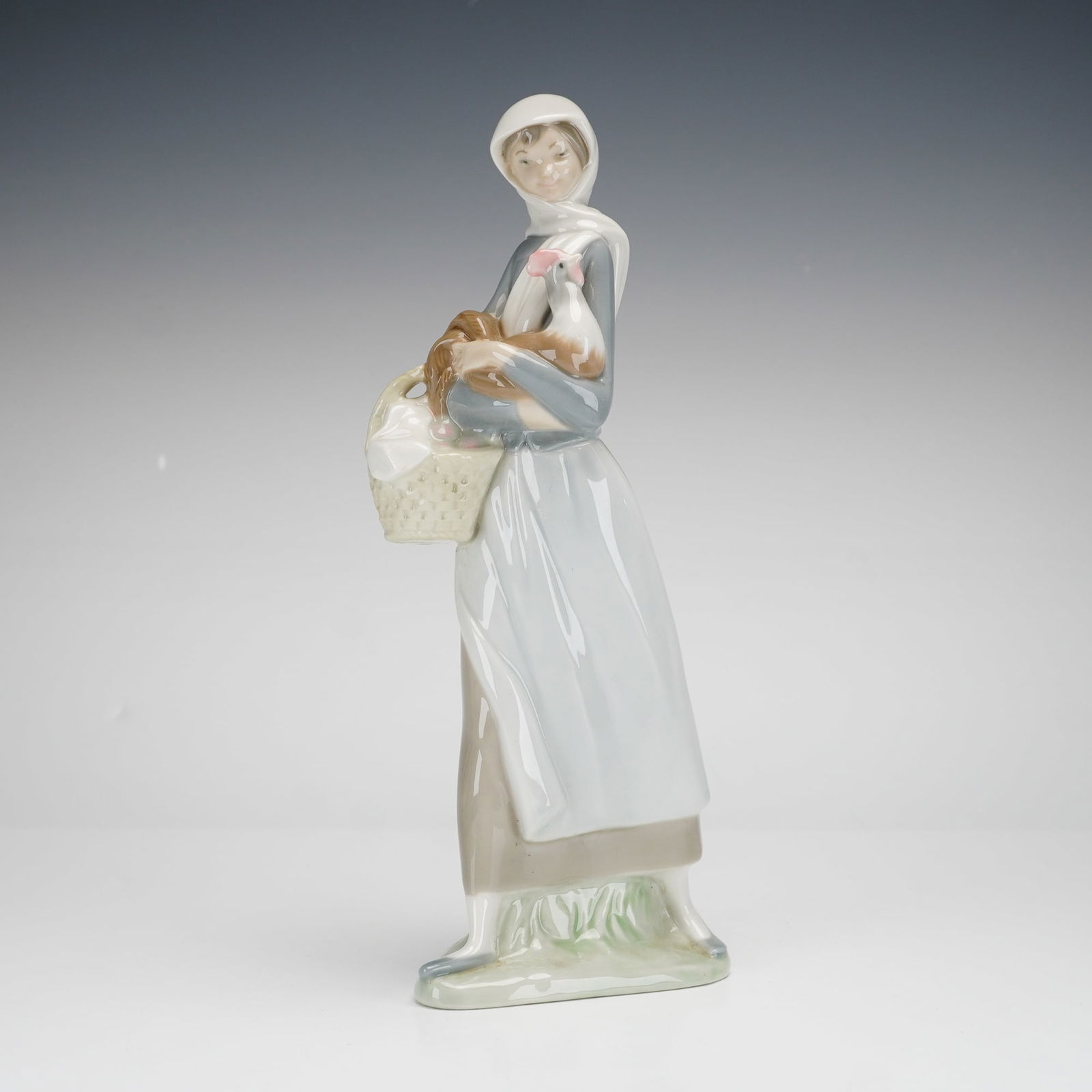Lladro Porcelain Figurine, Girl with Cockerel 1004591: This Lladro glazed porcelain figurine depicts a slender young woman in traditional rural attire. She wears a white headscarf, a blue long-sleeved bodice, and a white apron over a long, earth-toned ski