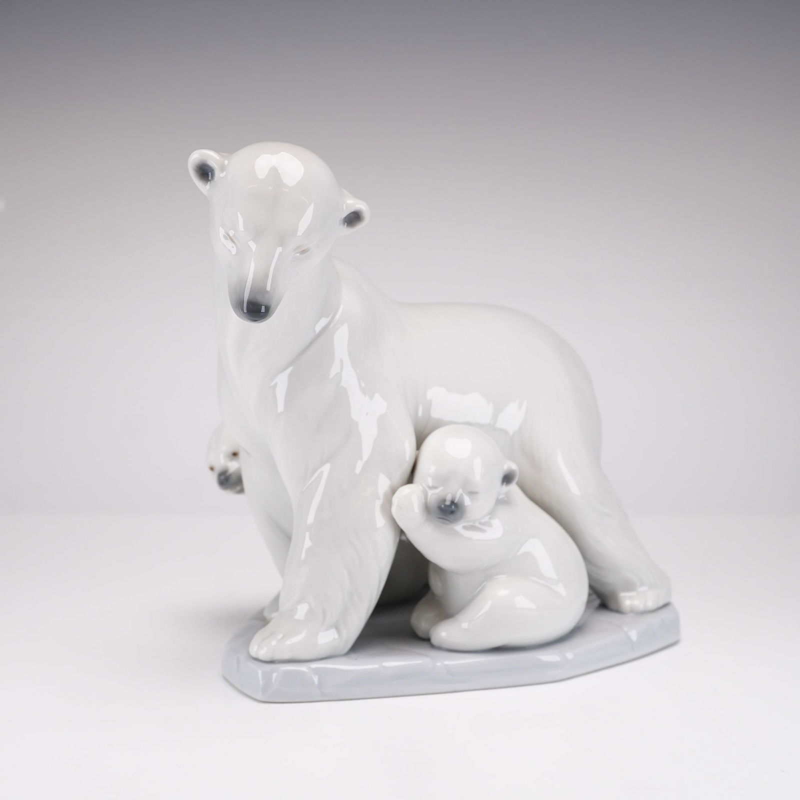 Lladro Porcelain Polar Bear Figurine, Arctic Family 1006745: This Lladro glazed porcelain figurine, titled Arctic Family (model 6745), was designed by sculptor Juan Huerta. The piece depicts a mother polar bear standing on a textured, ice-like base with two cub