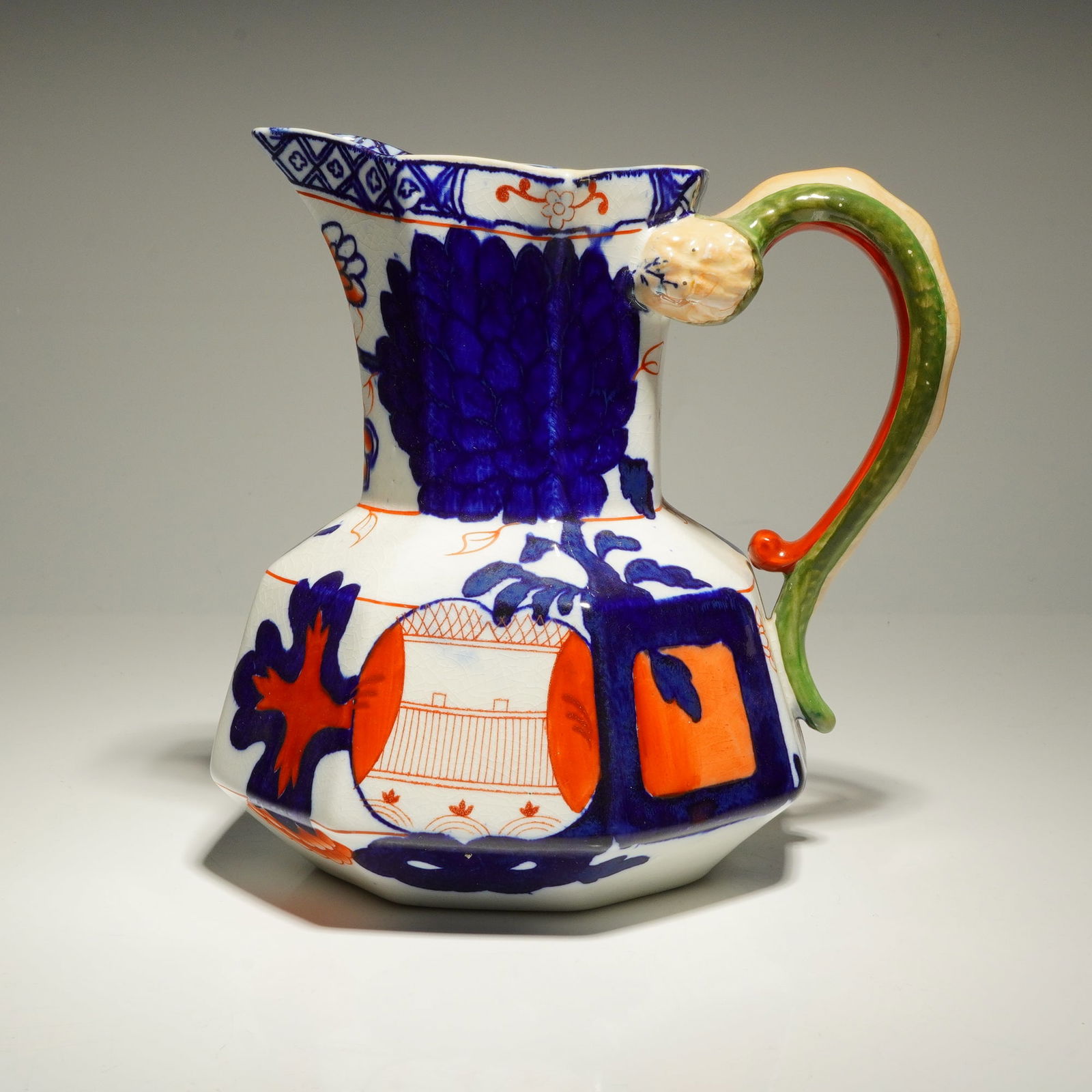 Royal Doulton Hydra Jug D2466: Hydra jug designed with octagonal body decorated in the D2466 pattern. The vessel is finished in an Imari-inspired palette of cobalt blue and burnt orange against a cream ground. It is characterized