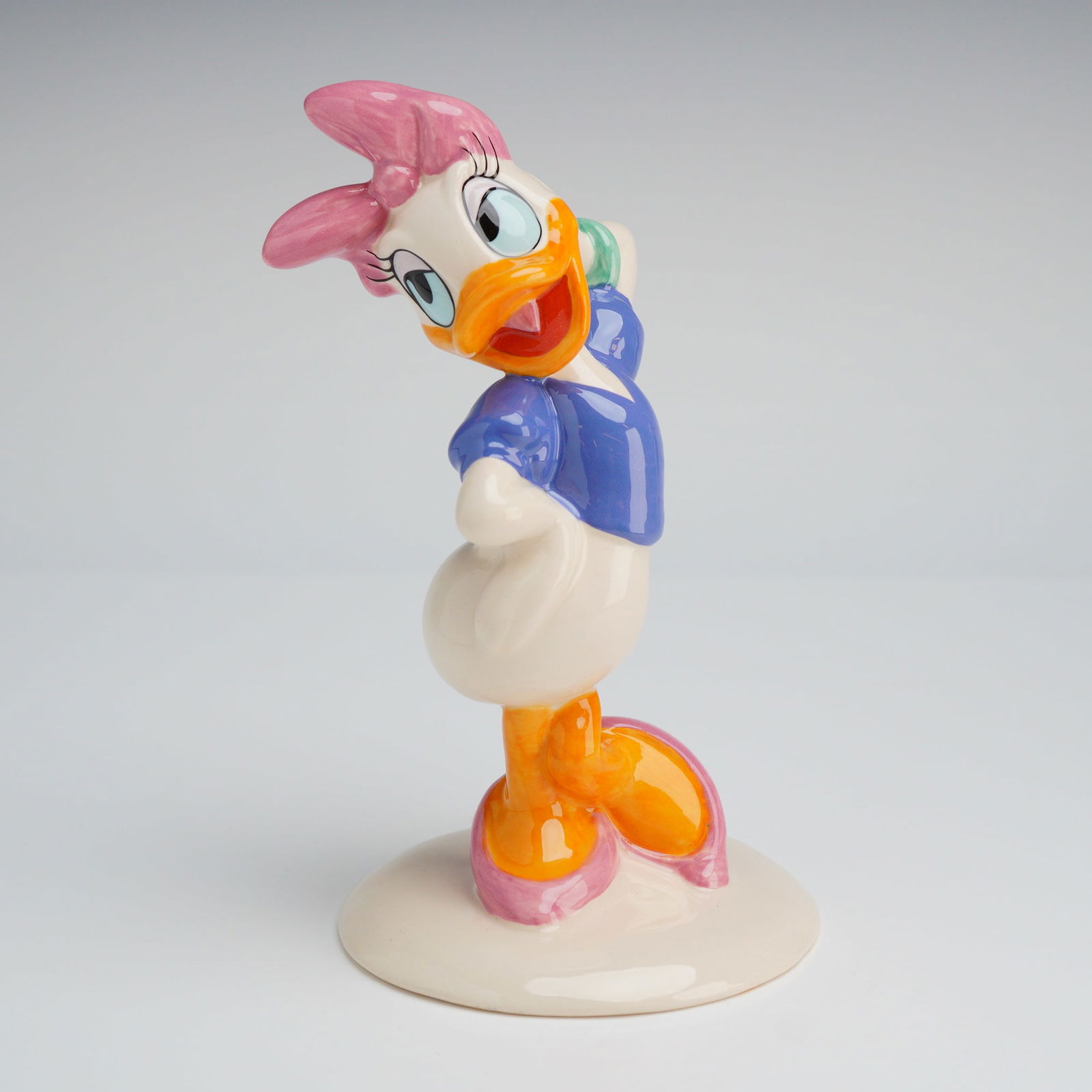 Royal Doulton Mickey Mouse Collection Daisy Duck Figurine MM4: A glazed porcelain figurine manufactured by Royal Doulton as part of The Mickey Mouse Collection, model number MM 4, depicting the Disney character Daisy Duck. The figurine is hand made and decorated