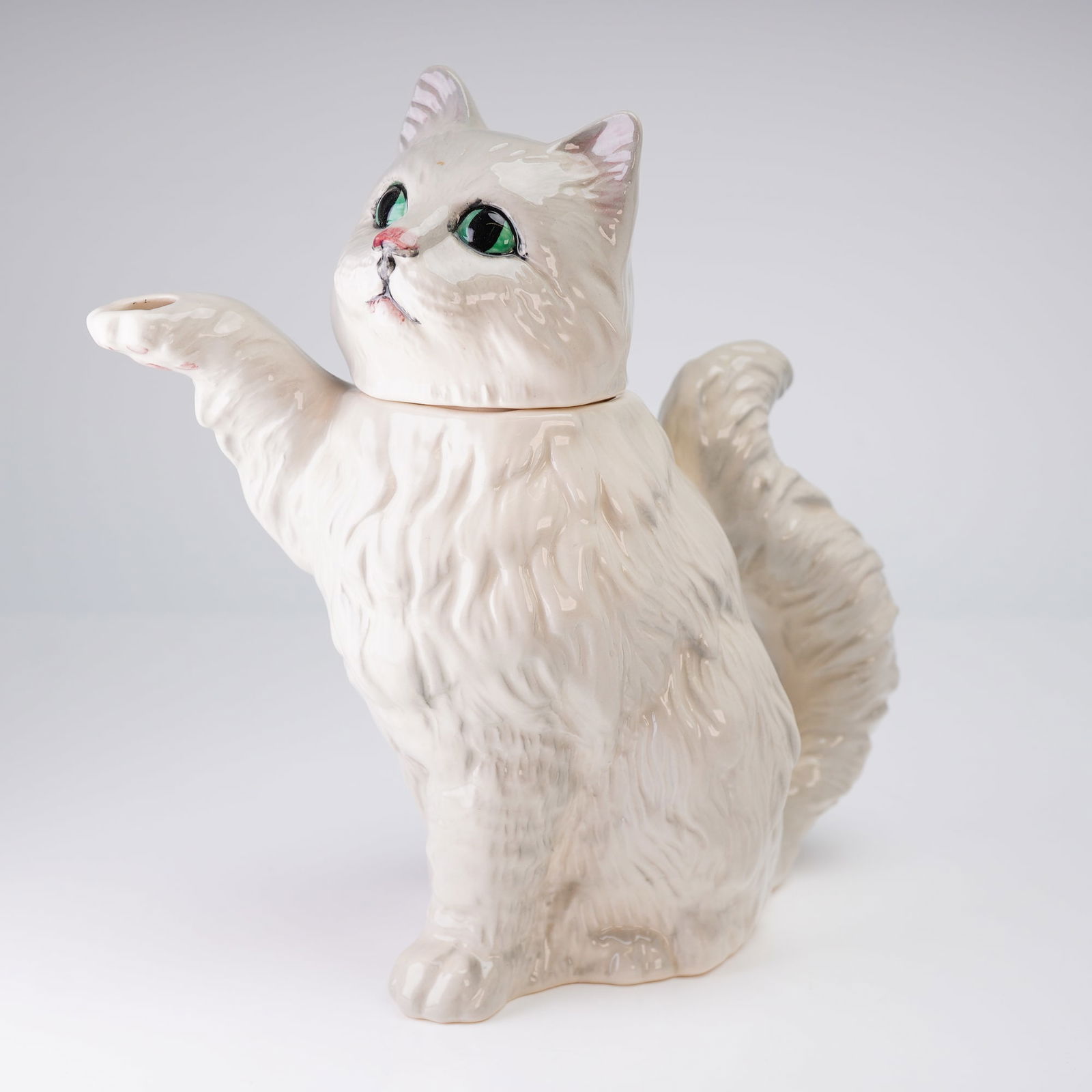 Beswick White Persian Cat Novelty Teapot: A novelty figural teapot manufactured by Beswick Pottery, England, modeled as a seated long-haired white cat, often identified as a Persian breed. The teapot is constructed of glazed earthenware or ce