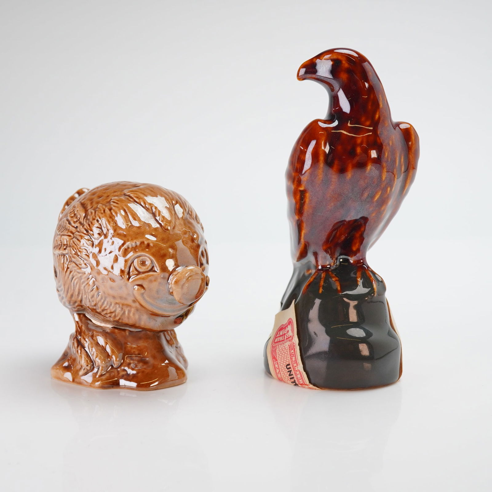 2pc Beswick Beneagles Scotch Whisky Miniature Decanters: A pair of Beswick ceramic miniature scotch whisky bottles produced for Beneagles by Peter Thomson (Perth) Ltd. The first figurine depicts a golden eagle perched on a dark base, modeled by J.G. Tongue