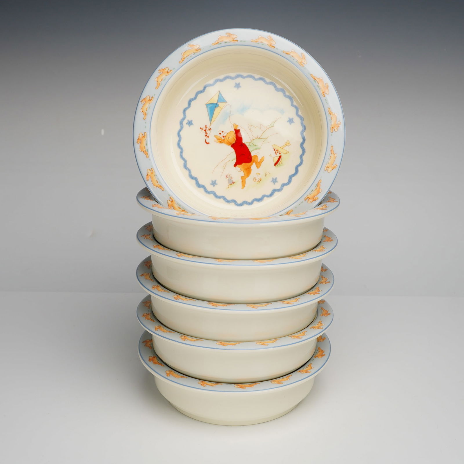 6pc Royal Doulton Bunnykins Shining Stars Cereal Bowls, H.5318: A collection of six Royal Doulton bone china bowls in the Bunnykins Shining Stars pattern, H.5318. Each vessel features a central polychrome illustration depicting a rabbit in a red coat flying a kite