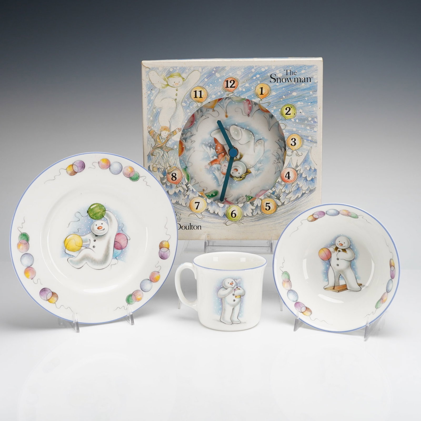 4pc Royal Doulton The Snowman Gift Collection Cup, Clock, Bowl, & Plate: 4pc Royal Doulton The Snowman Gift Collection bone china nursery set, dated 1985. The collection includes a plate, a bowl, a cup, and a battery-operated wall clock. Each piece features colorful printe