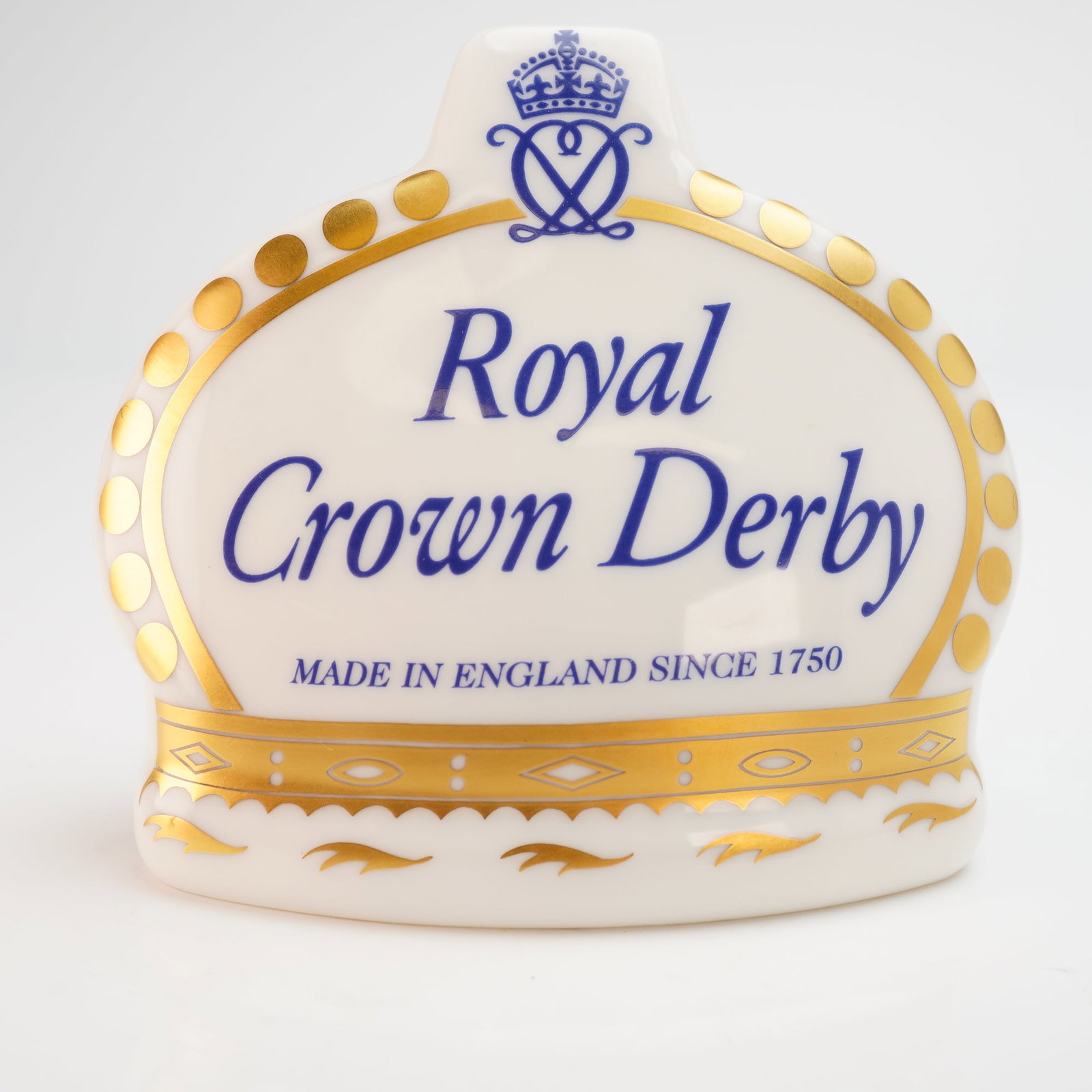 Royal Crown Derby Collectors Guild 10th Anniversary Display Sign: A Royal Crown Derby English bone china advertising display sign. The piece is modeled in the form of a stylized crown with a white glazed finish and gold gilt accents. The front face features the Roya