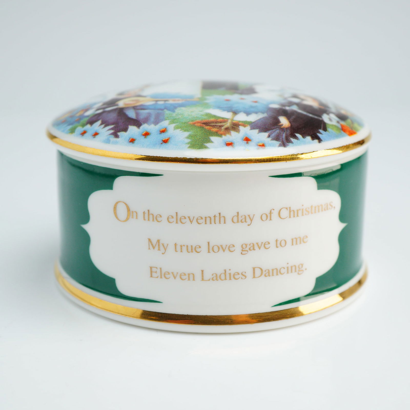 Wedgwood Bone China Lidded Box, Eleven Ladies Dancing: A Wedgwood bone china lidded trinket box from The Twelve Days of Christmas series, representing the eleventh edition, Eleven Ladies Dancing. The circular vessel features a dark green body with a white