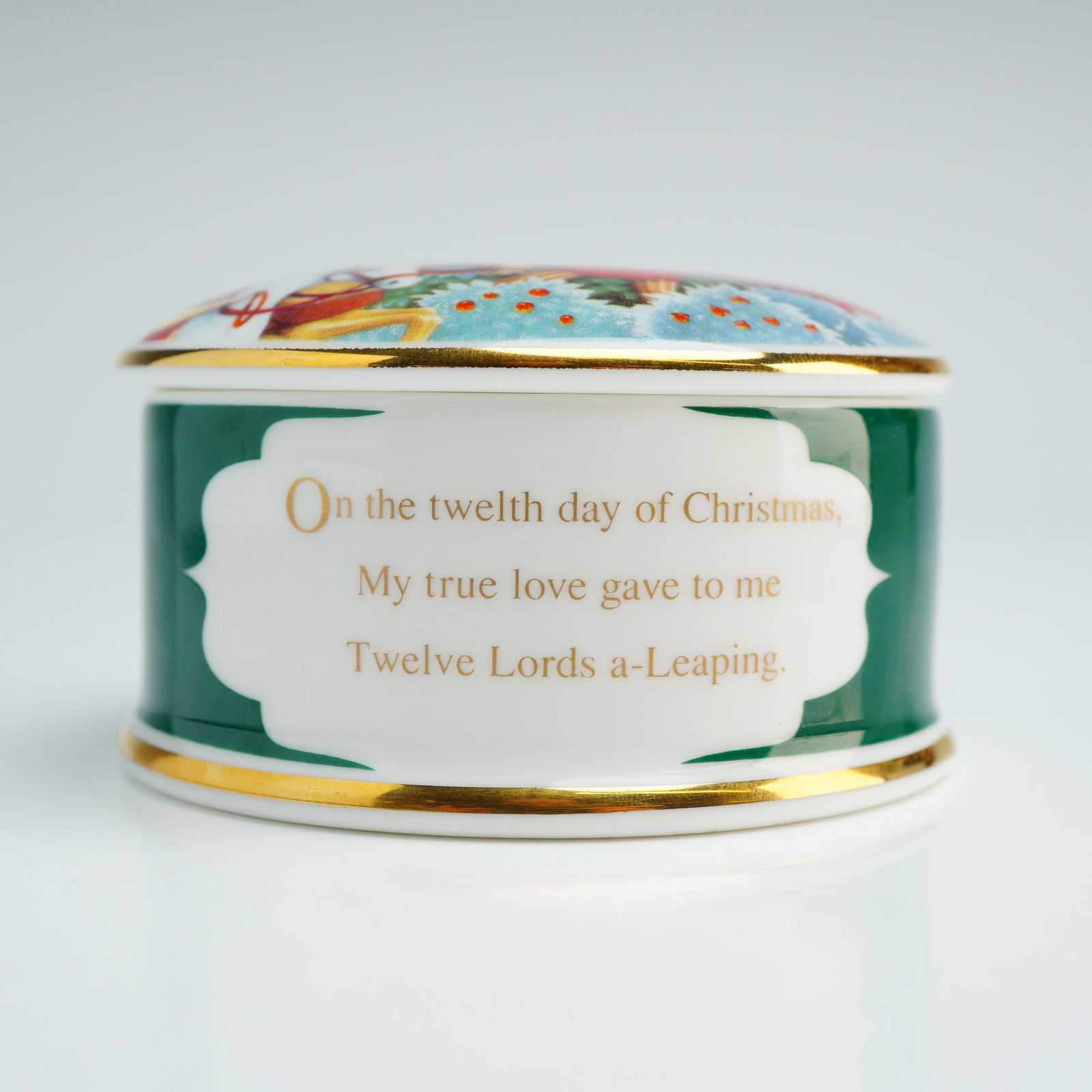 Wedgwood Bone China Lidded Box, 12 Lords a Leaping: This Wedgwood round bone china lidded box is part of the Twelve Days of Christmas series, specifically featuring the 12 Lords of Leaping. The circular trinket box is constructed with a deep green glaz