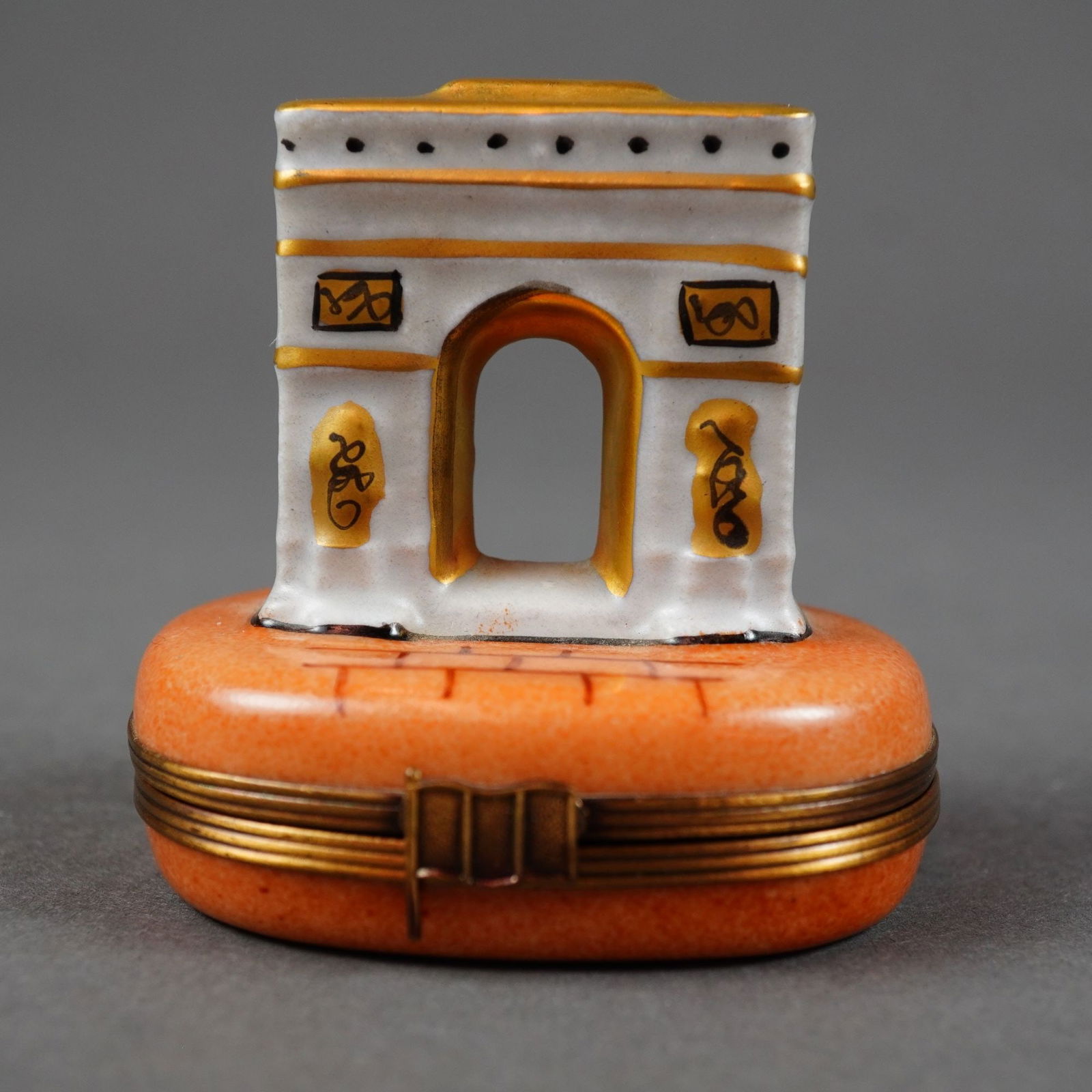 Limoges Arc de Triomphe Porcelain Trinket Box: This Limoges hard-paste porcelain hinged box features a sculptural topper depicting the Arc de Triomphe in Paris. The arch is decorated with hand-painted gilded borders and black line-work highlightin