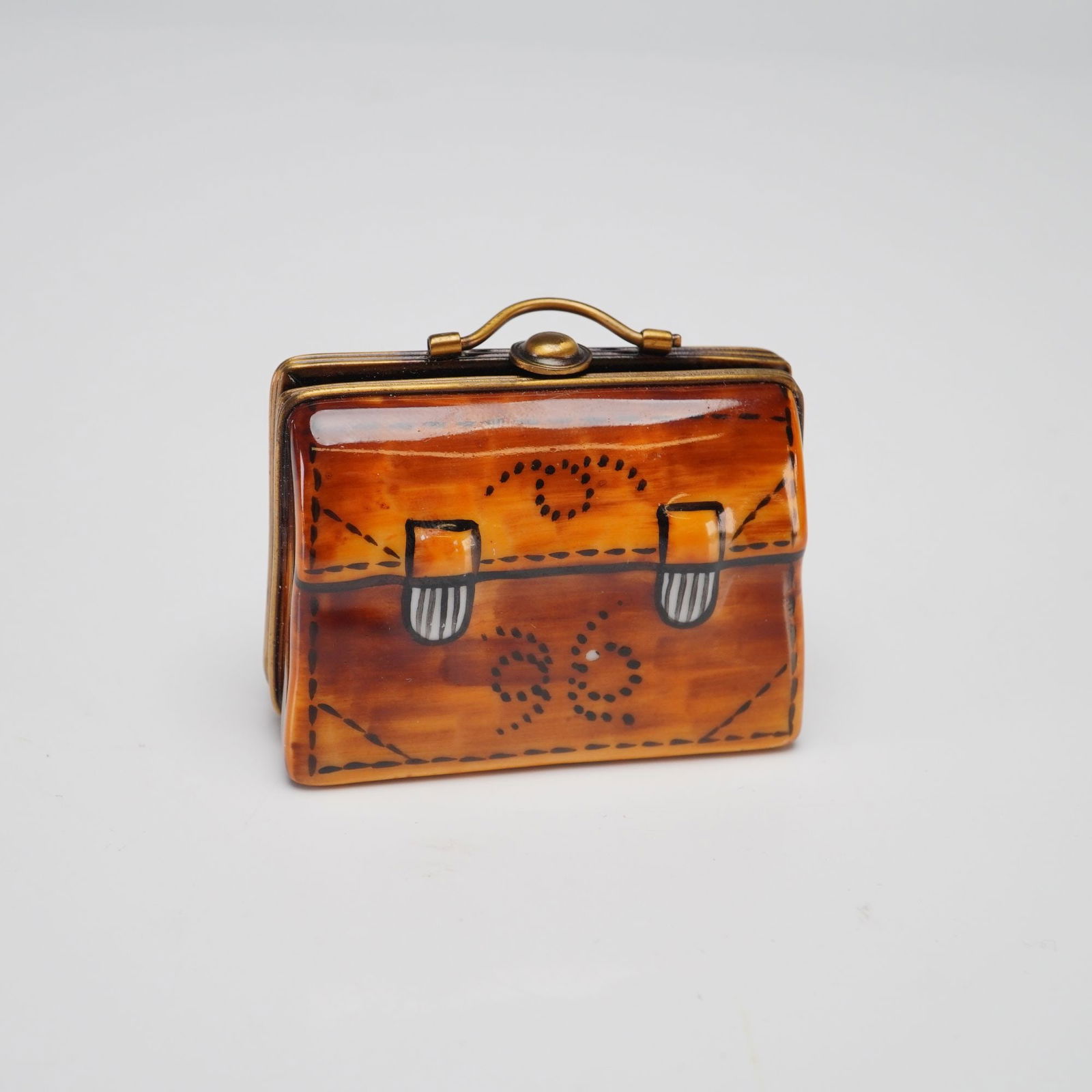 Rochard Limoges Briefcase Trinket Box: A fine porcelain miniature hinged trinket box manufactured by Rochard in Limoges, France. The box is designed in the form of a briefcase or satchel and features hand-painted decoration with a warm, tr