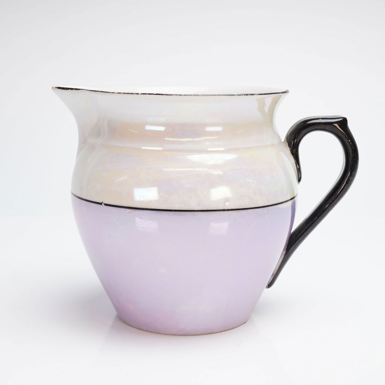 Lusterware Creamer Pitcher: The Art Deco style creamer pitcher is likely dating from the early to mid-20th century. The body features a horizontally divided glaze scheme: the upper section is finished in an iridescent white lust