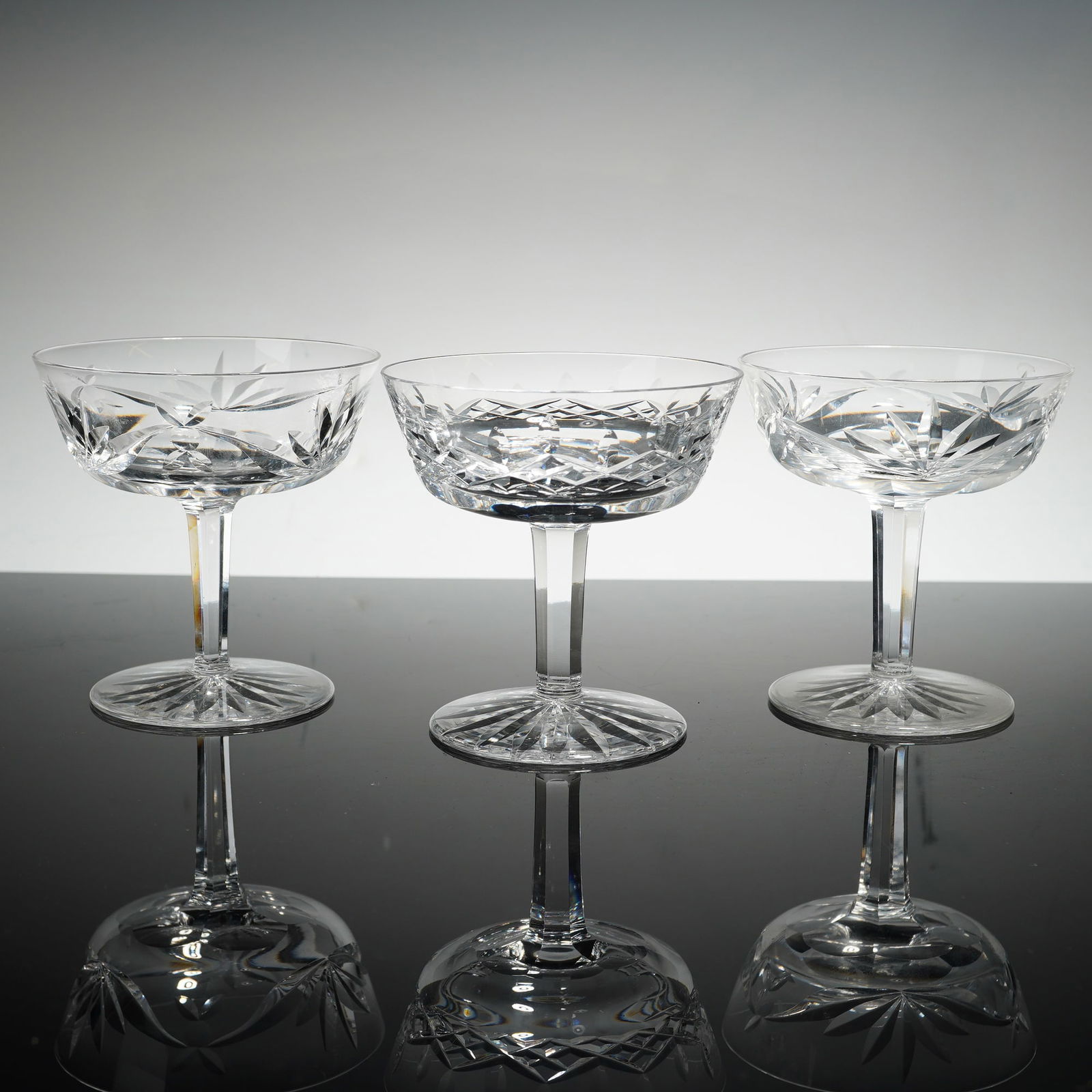 3pc Waterford Crystal Lismore and Ashling Champagne Coupes: This set features two of the company's most celebrated designs: two glasses in the Ashling pattern, characterized by long vertical wedge cuts over a band of diamond cuts, and one center glass in the L