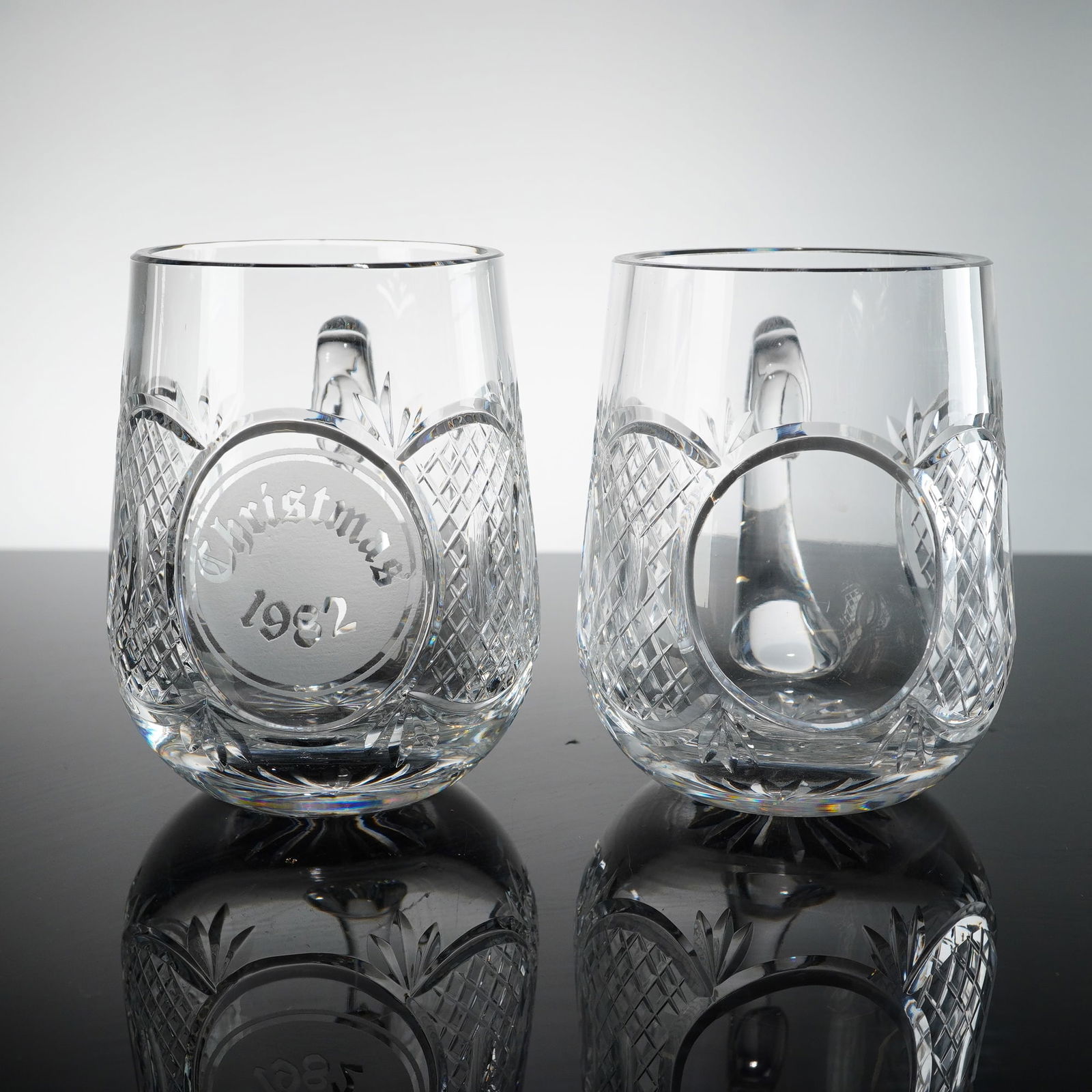 Waterford Crystal Christmas 1982 Commemorative Tankard and Matching Mug: This is a pair of fine lead crystal tankards manufactured by Waterford. The set includes one commemorative piece featuring a frosted roundel etched with Christmas 1982 in decorative calligraphy and a