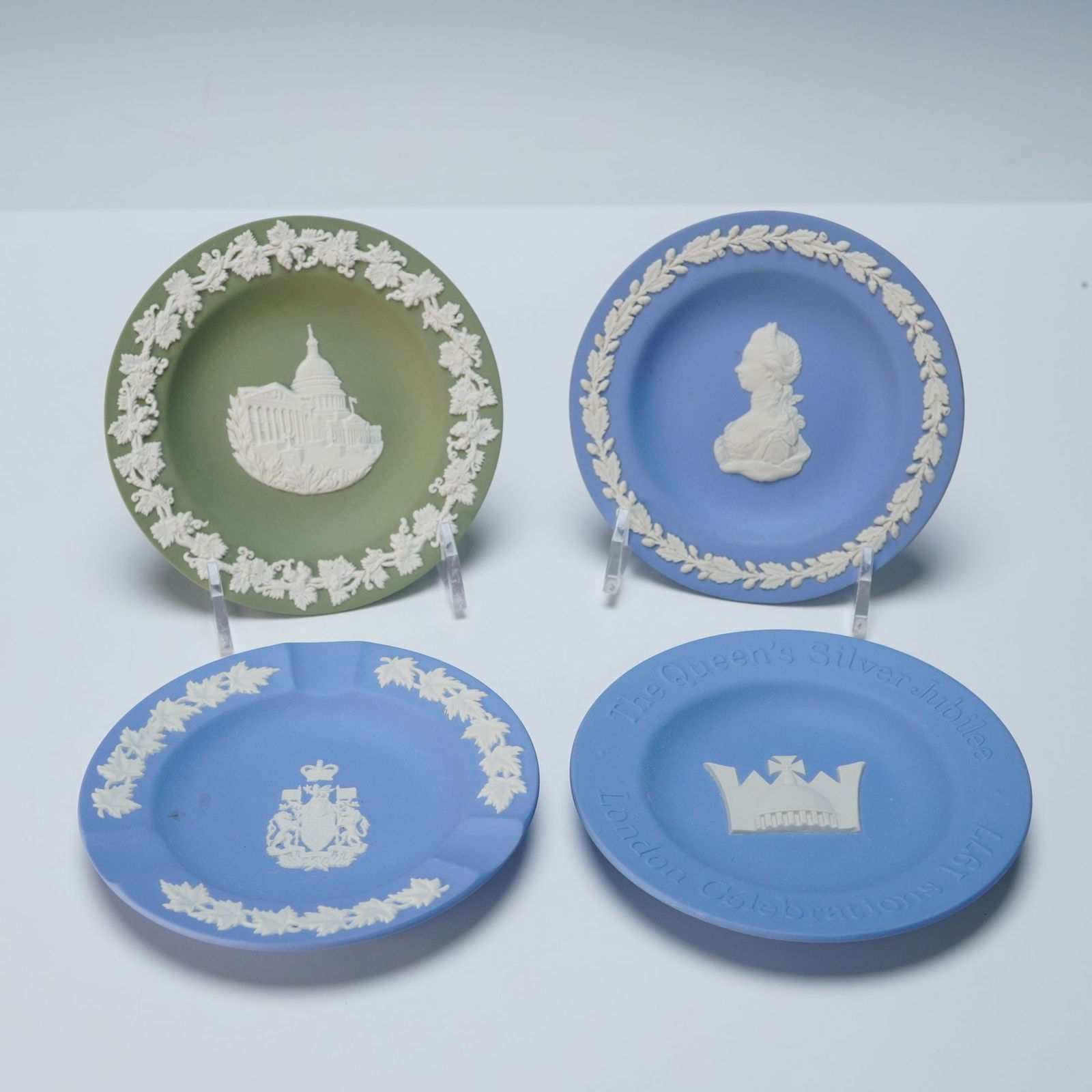 A Collection of Four Wedgwood Jasperware Commemorative Dishes: A collection of four Wedgwood Jasperware ceramic decorative trinket dishes, each featuring raised white Neoclassical-style bas-relief decoration, typically encircled by a foliate border. The collectio